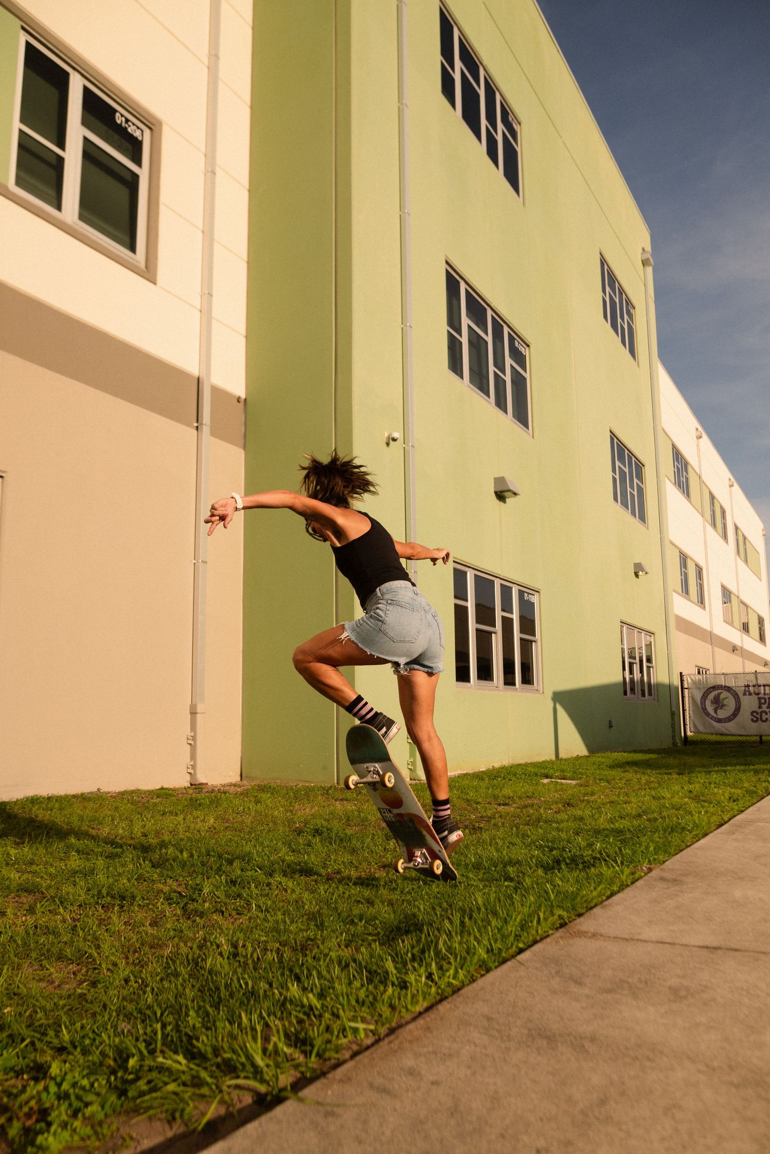Skateboarding sequence on a grassy slope next to a light-colored building.
