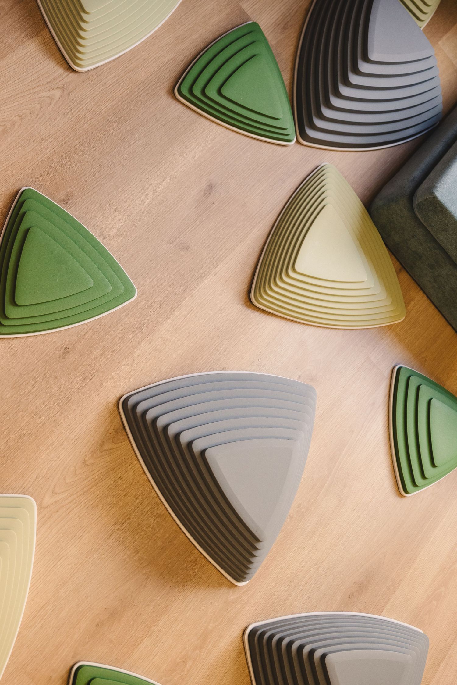 Colorful geometric wooden blocks arranged in triangular patterns on a light wooden surface.