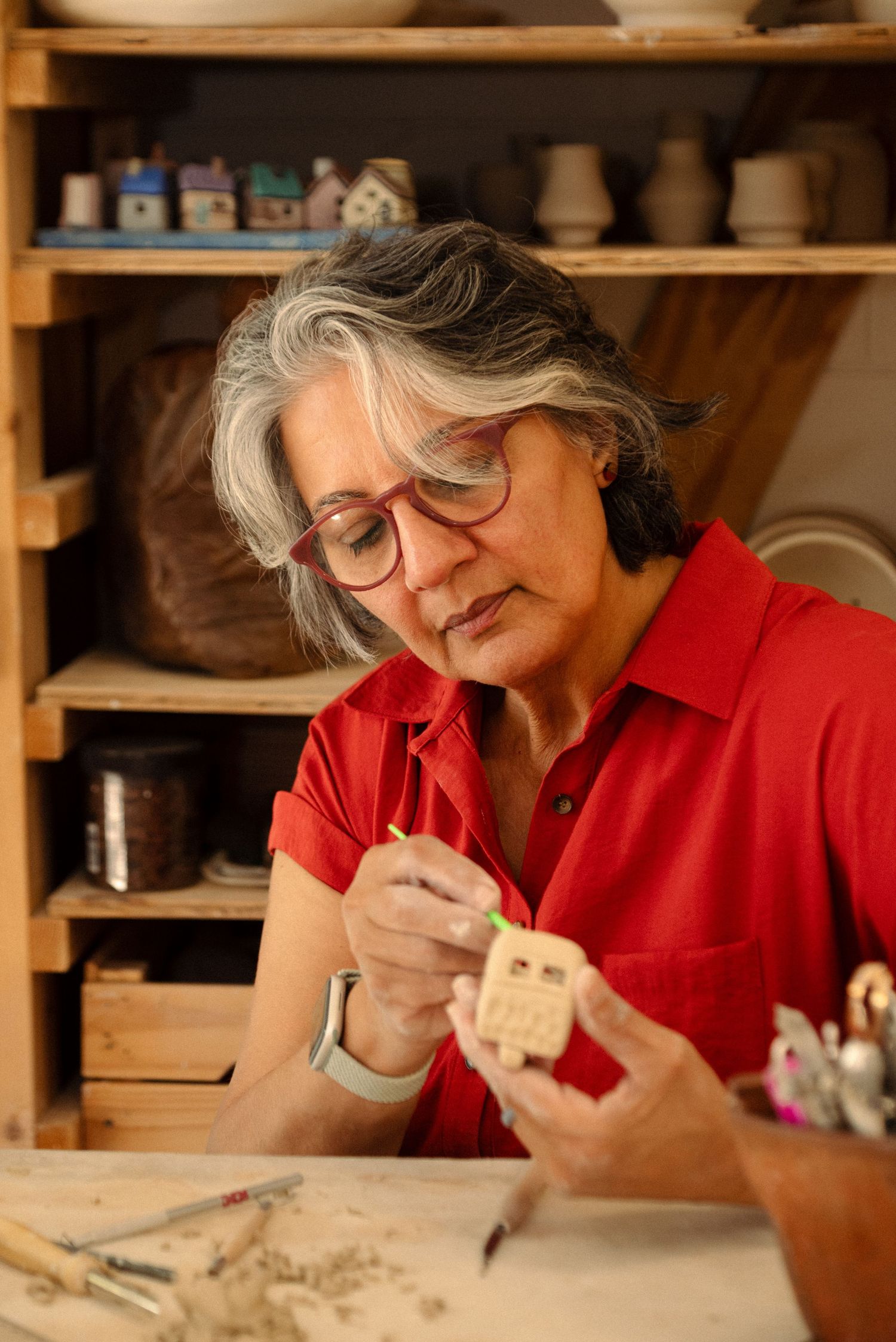 Artist working on detailed ceramic piece in a well-equipped studio.