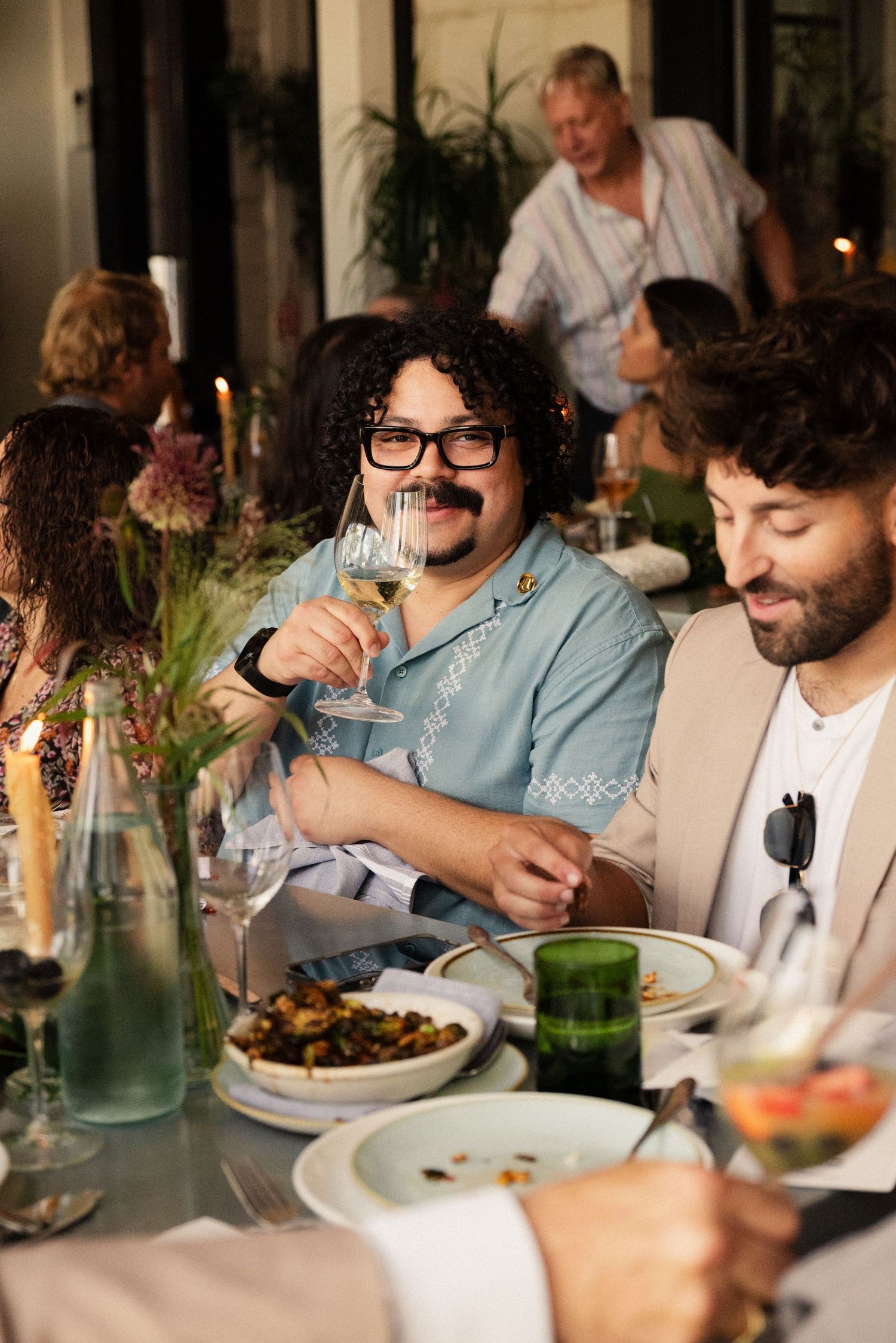 Guests enjoy a candlelit dinner party with wine and conversation.