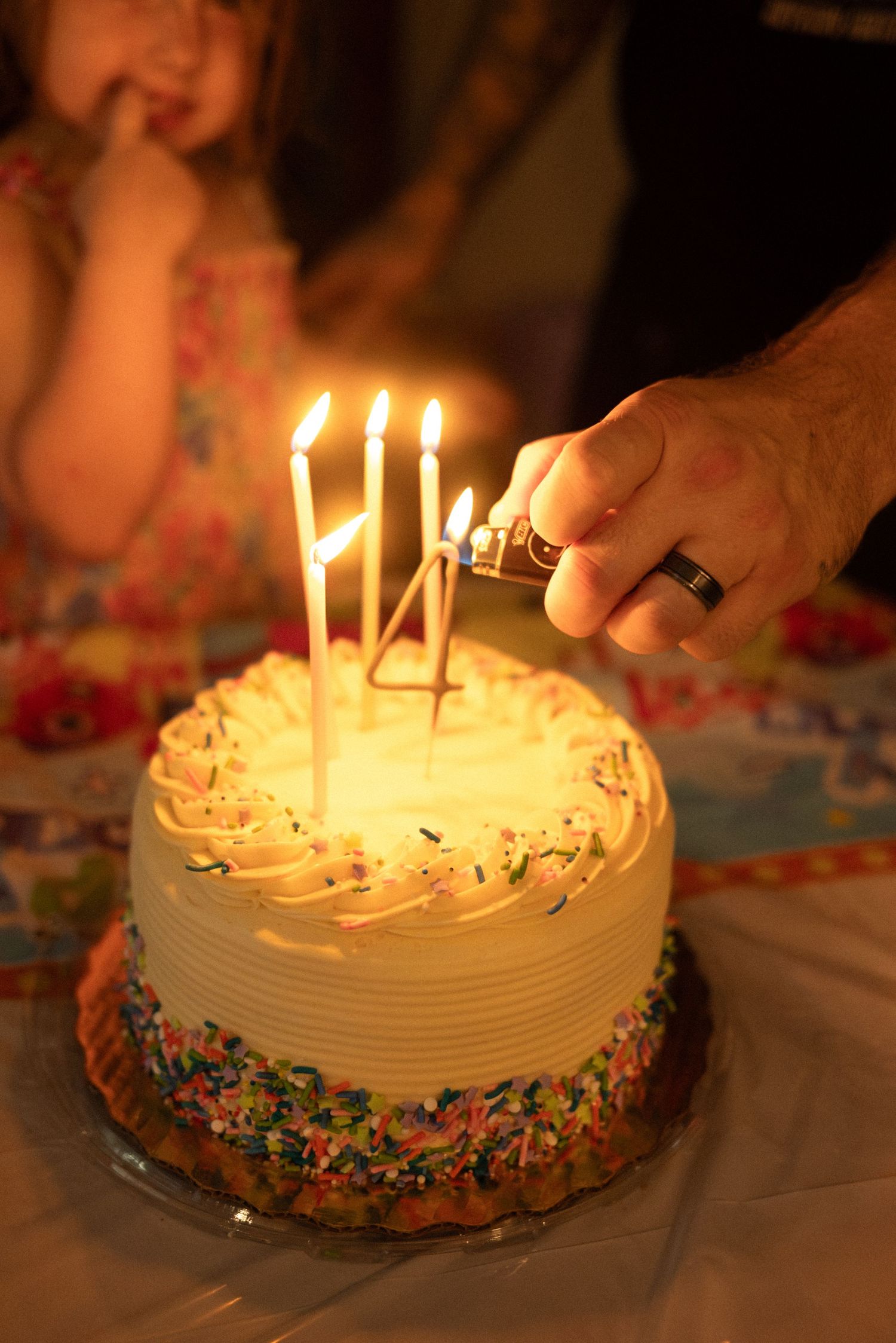 Birthday cake with lit candles and colorful sprinkles in warm lighting.