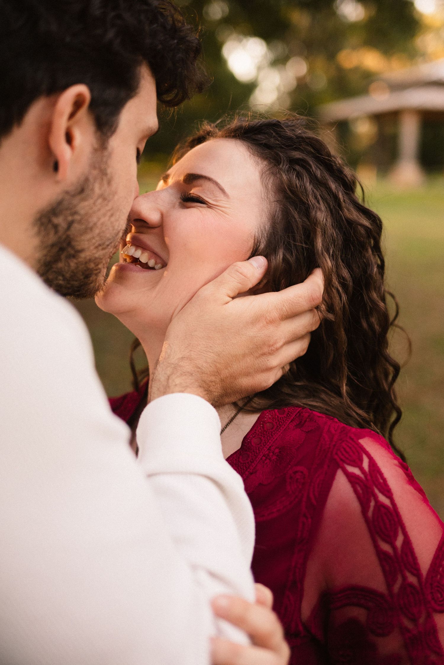 Couple sharing romantic kiss during sunset outdoor photo session.