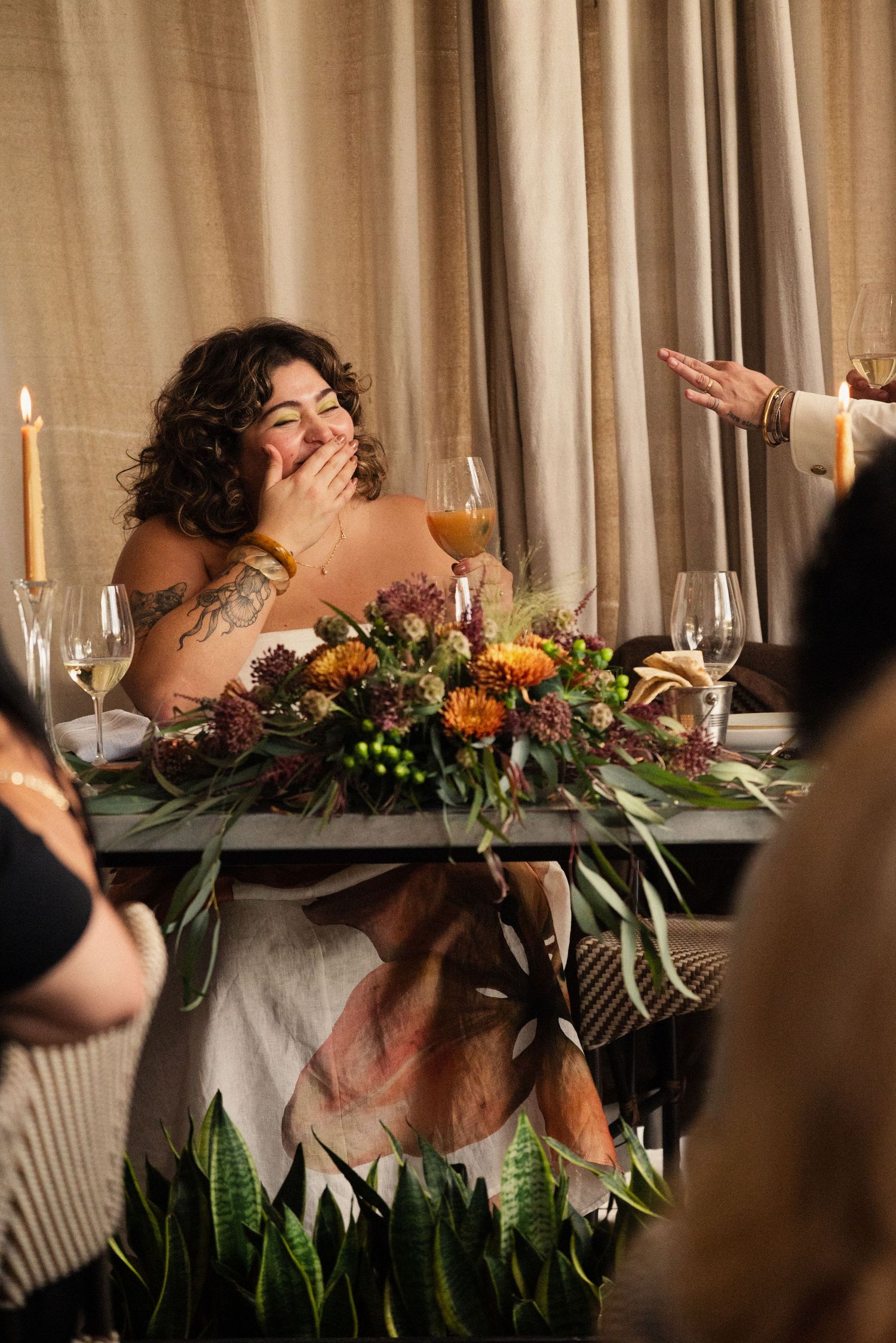 A candid moment captured during a wedding reception dinner with floral centerpieces.