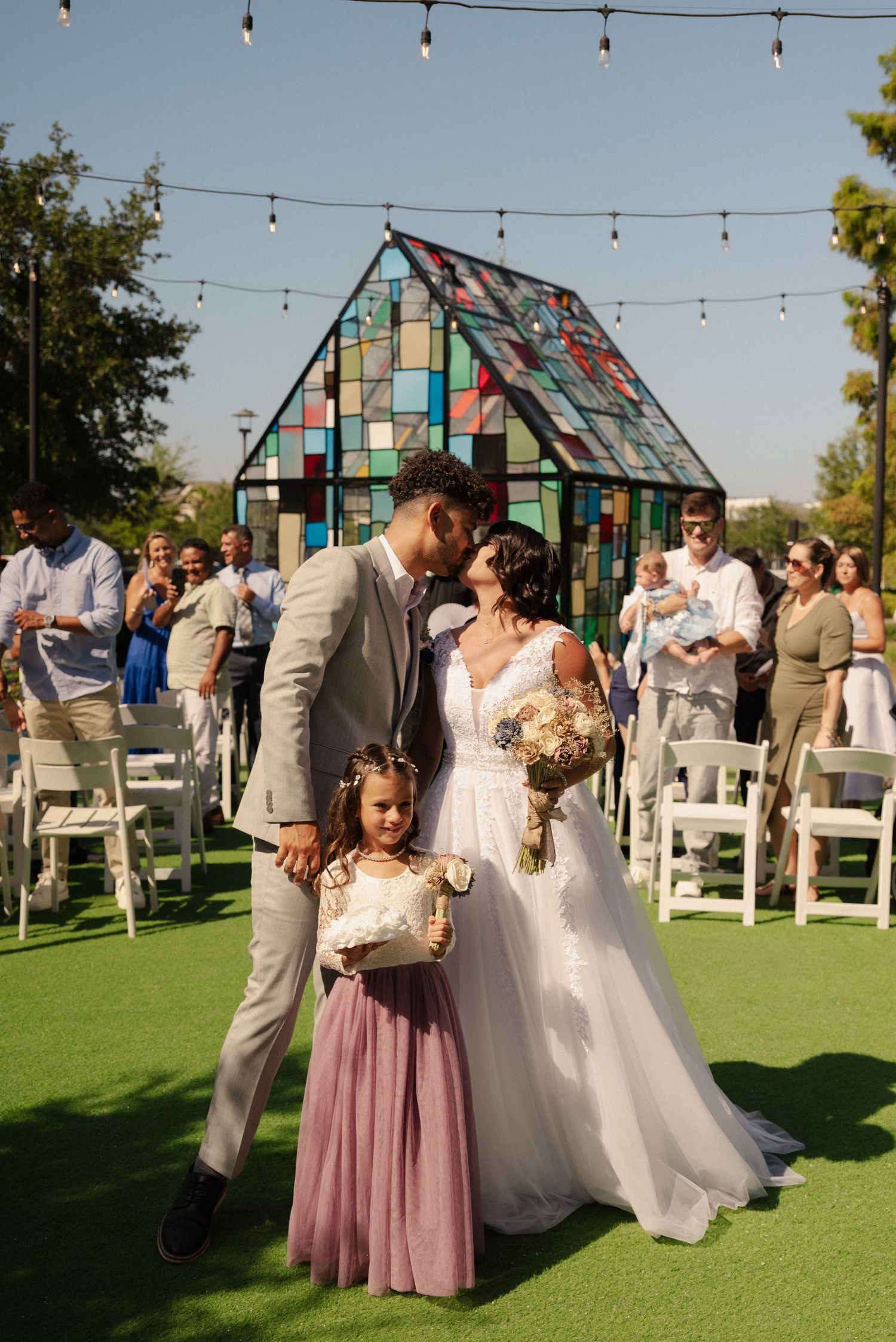 Outdoor wedding venue featuring a modern geometric greenhouse and string lights at sunset.