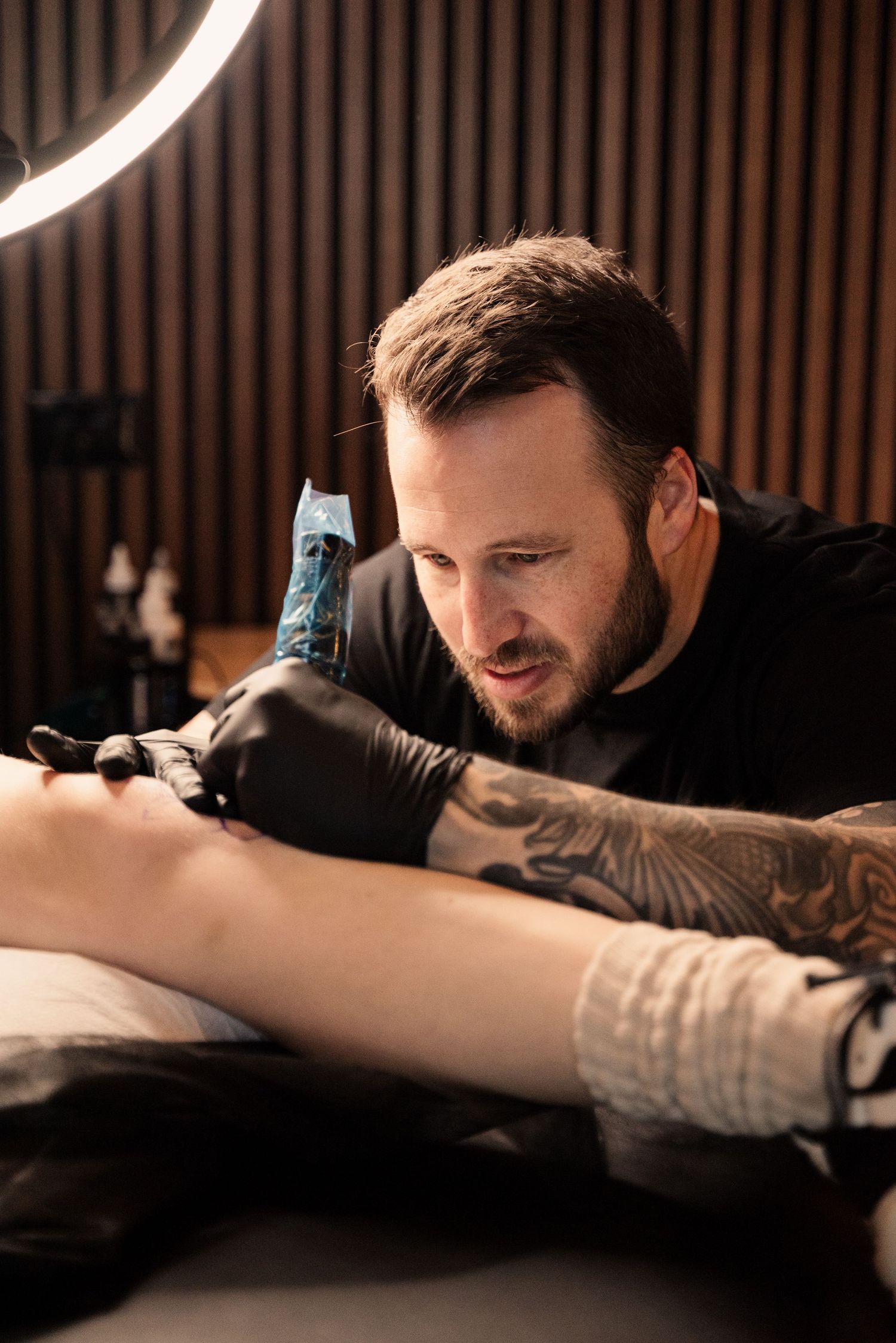 Tattoo artist concentrating while working on a client's arm.