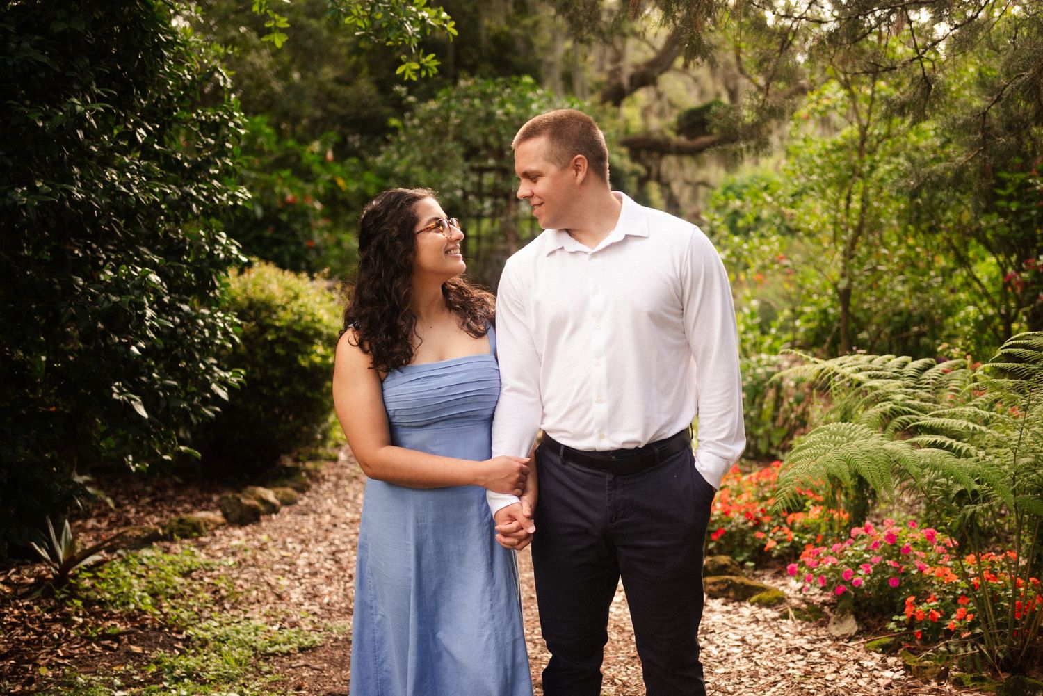 Couple enjoying a romantic moment together in a lush garden setting with blooming flowers.