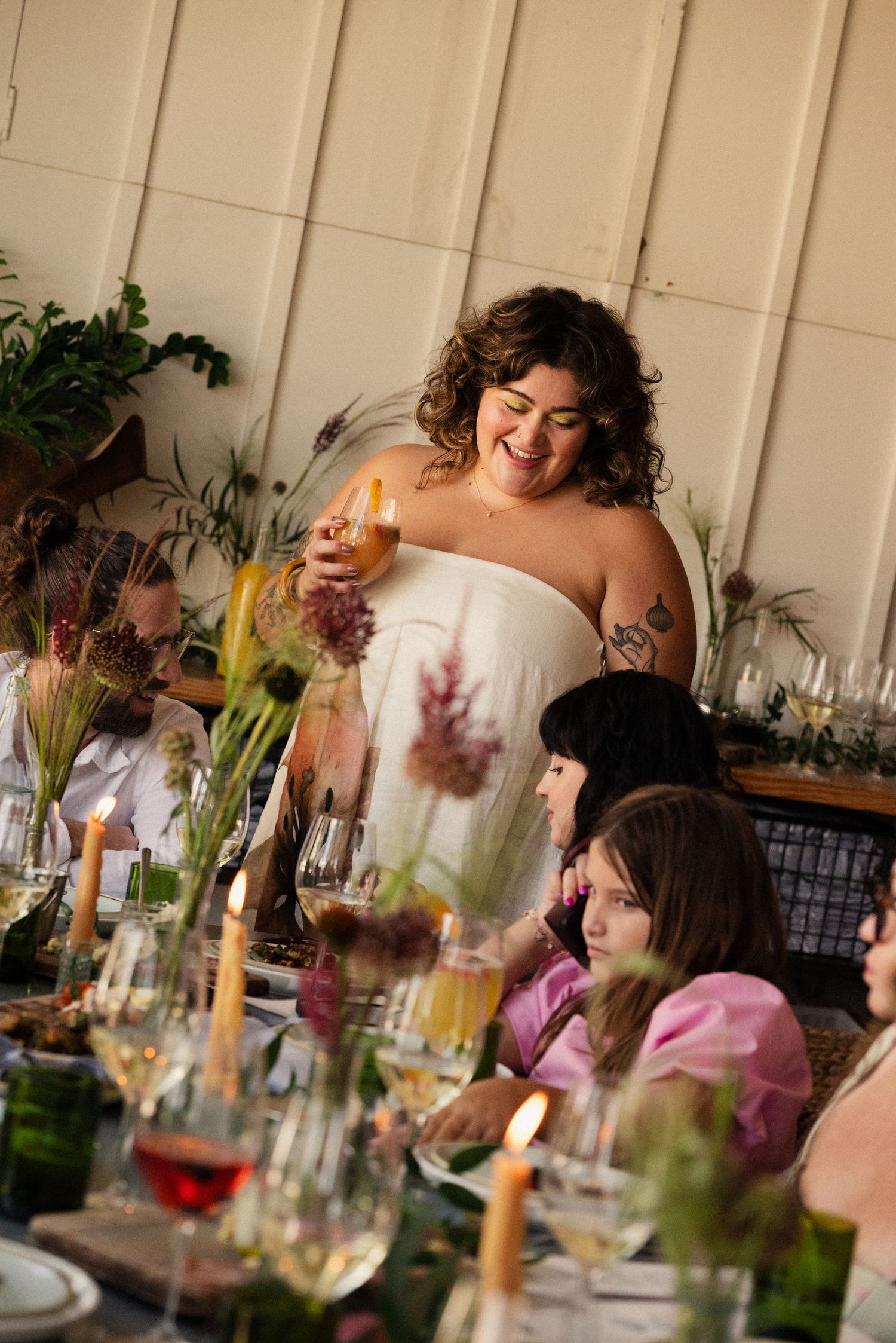 Wedding reception dinner table decorated with flowers and candles as guests enjoy the celebration.