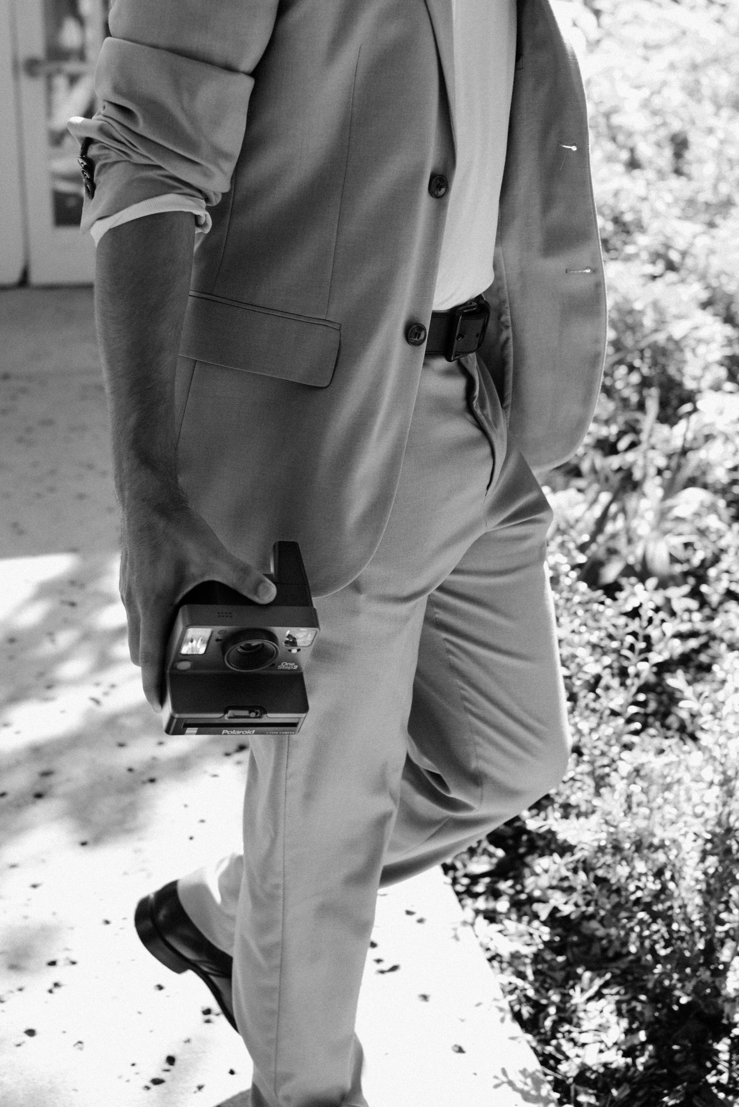 A black and white photo showing a person in a suit holding a vintage camera.