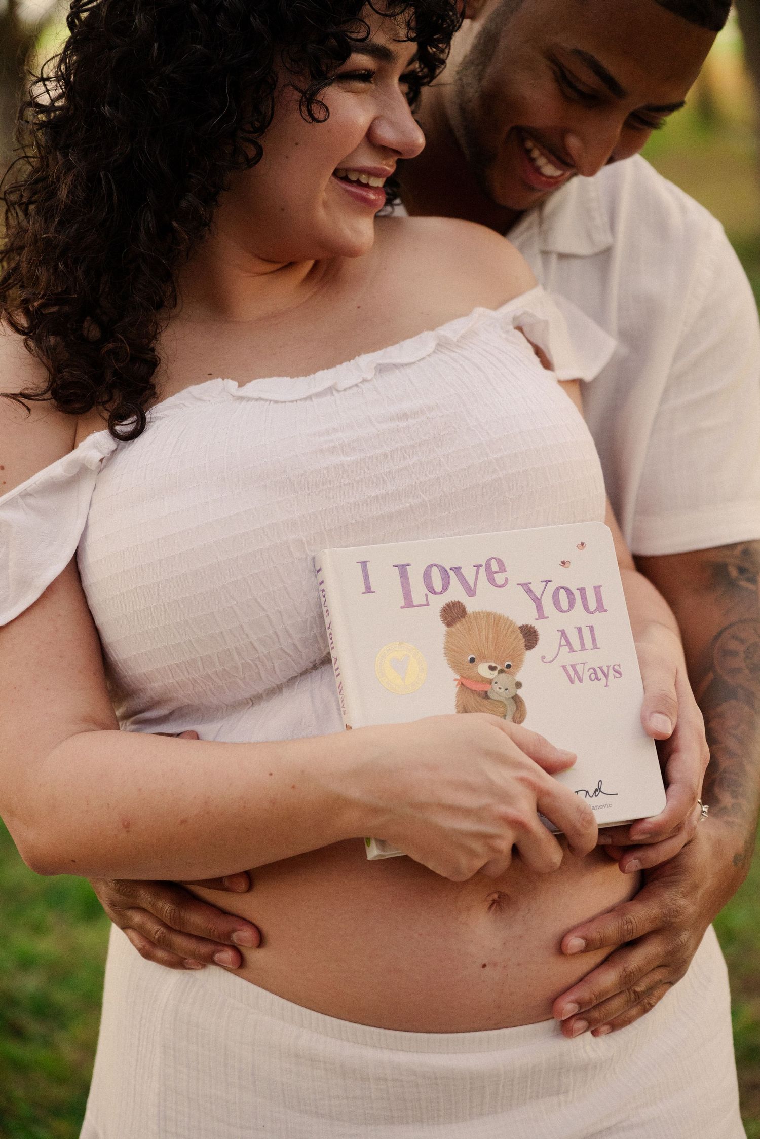 Couple shares intimate moment with 'I Love You' sign during maternity photo session.