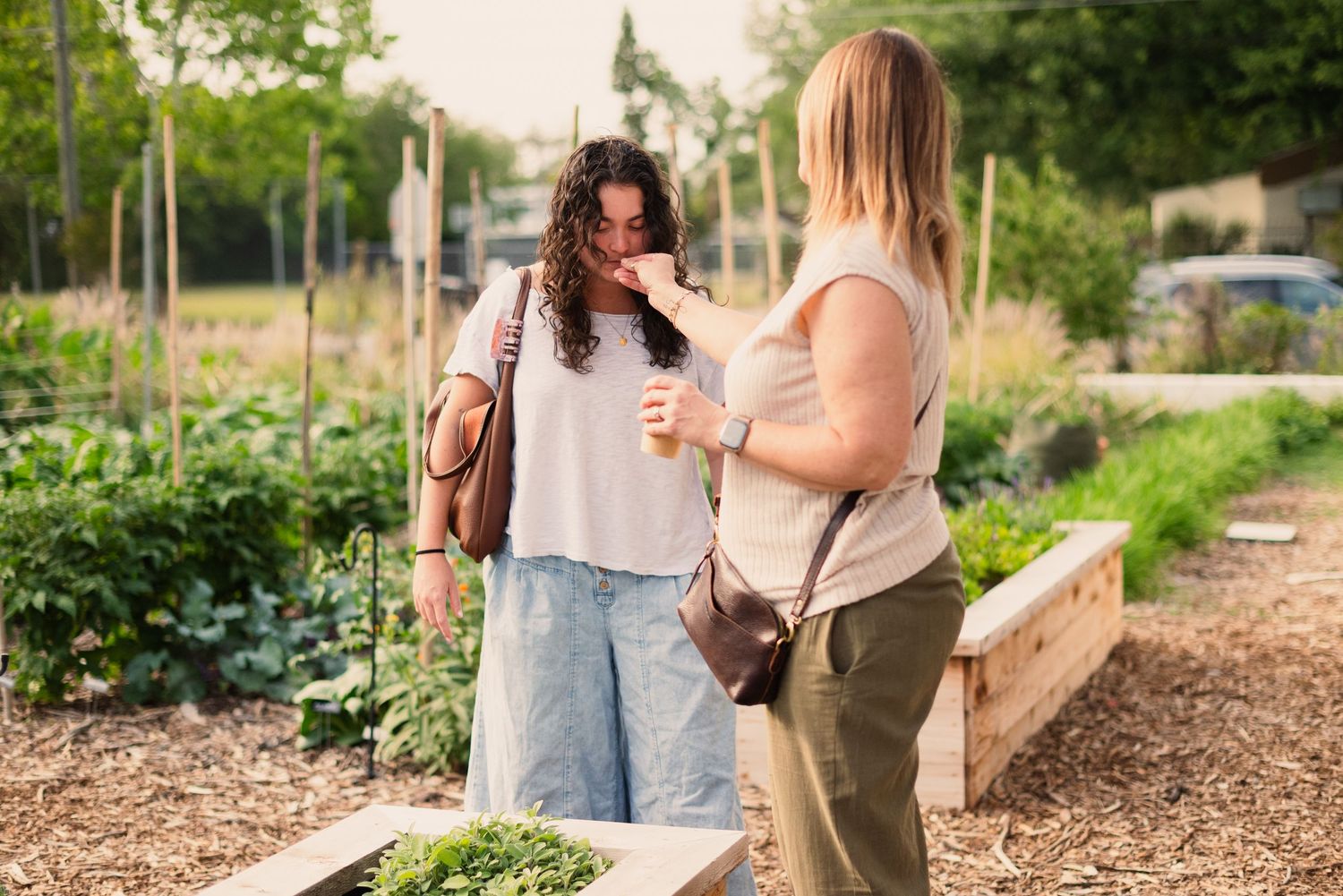 Two people chatting while holding drinks in a community garden setting.