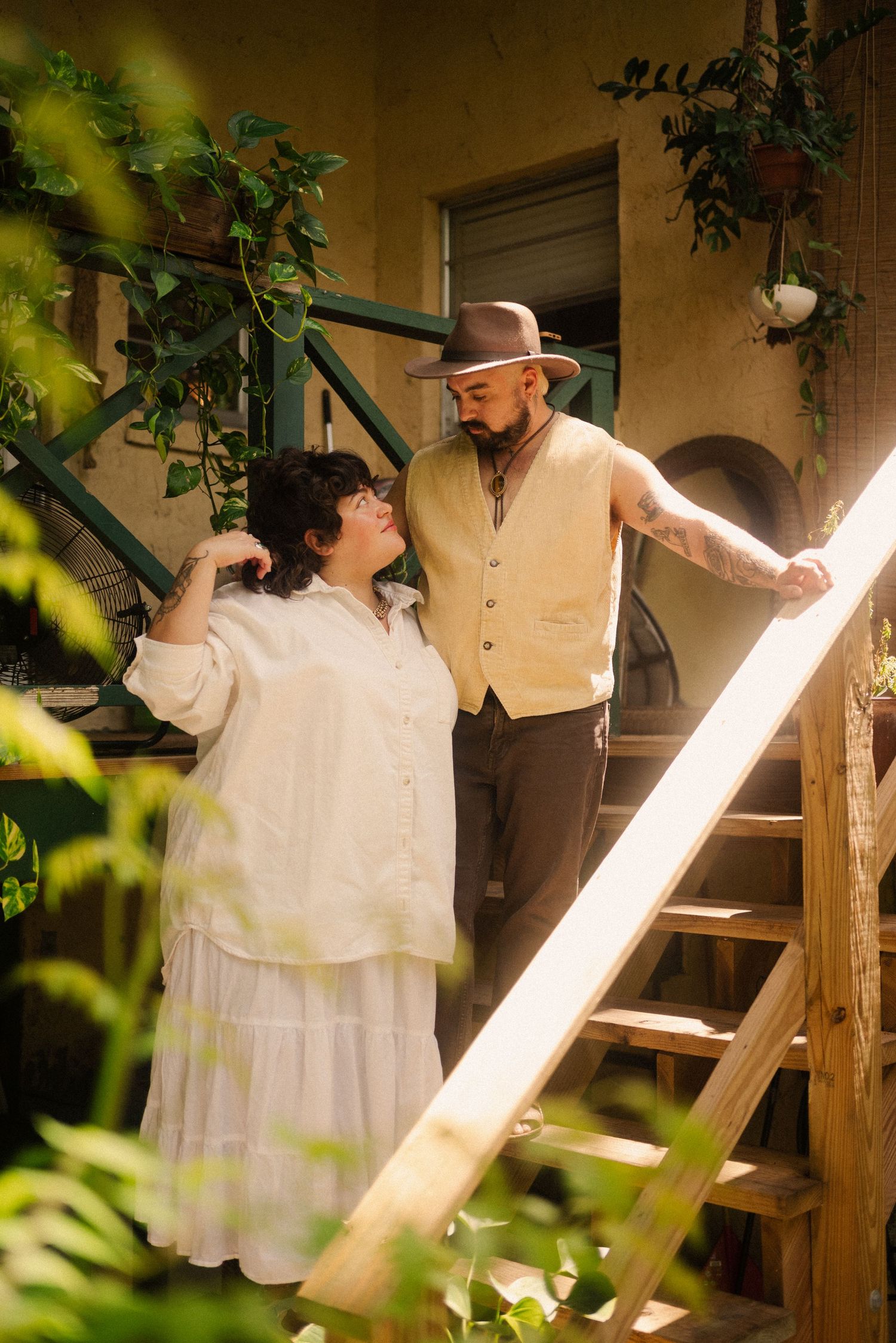 Couple in light colored clothing sharing romantic moment on outdoor porch.