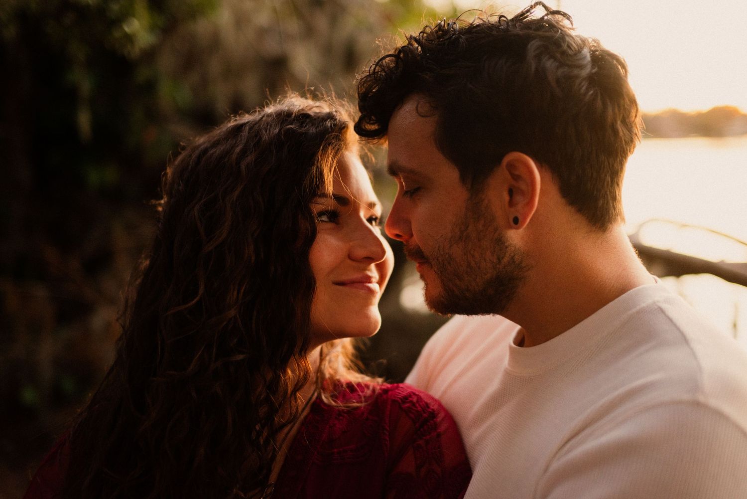 Intimate moments captured between a couple during golden hour by the water.