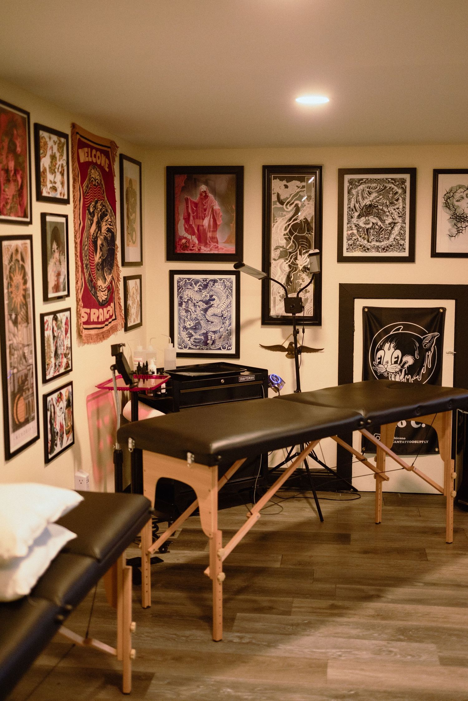 Massage therapy room with black tables and art-covered walls displaying various framed pieces.
