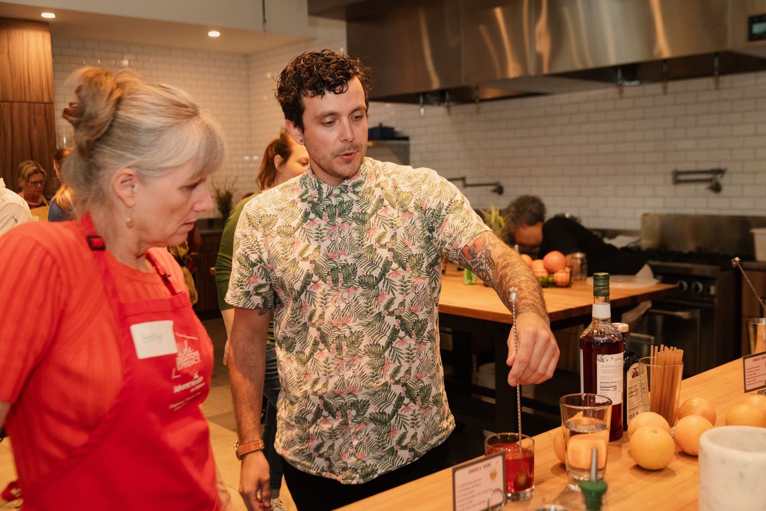 Participants learning mixology techniques in a professional kitchen environment.