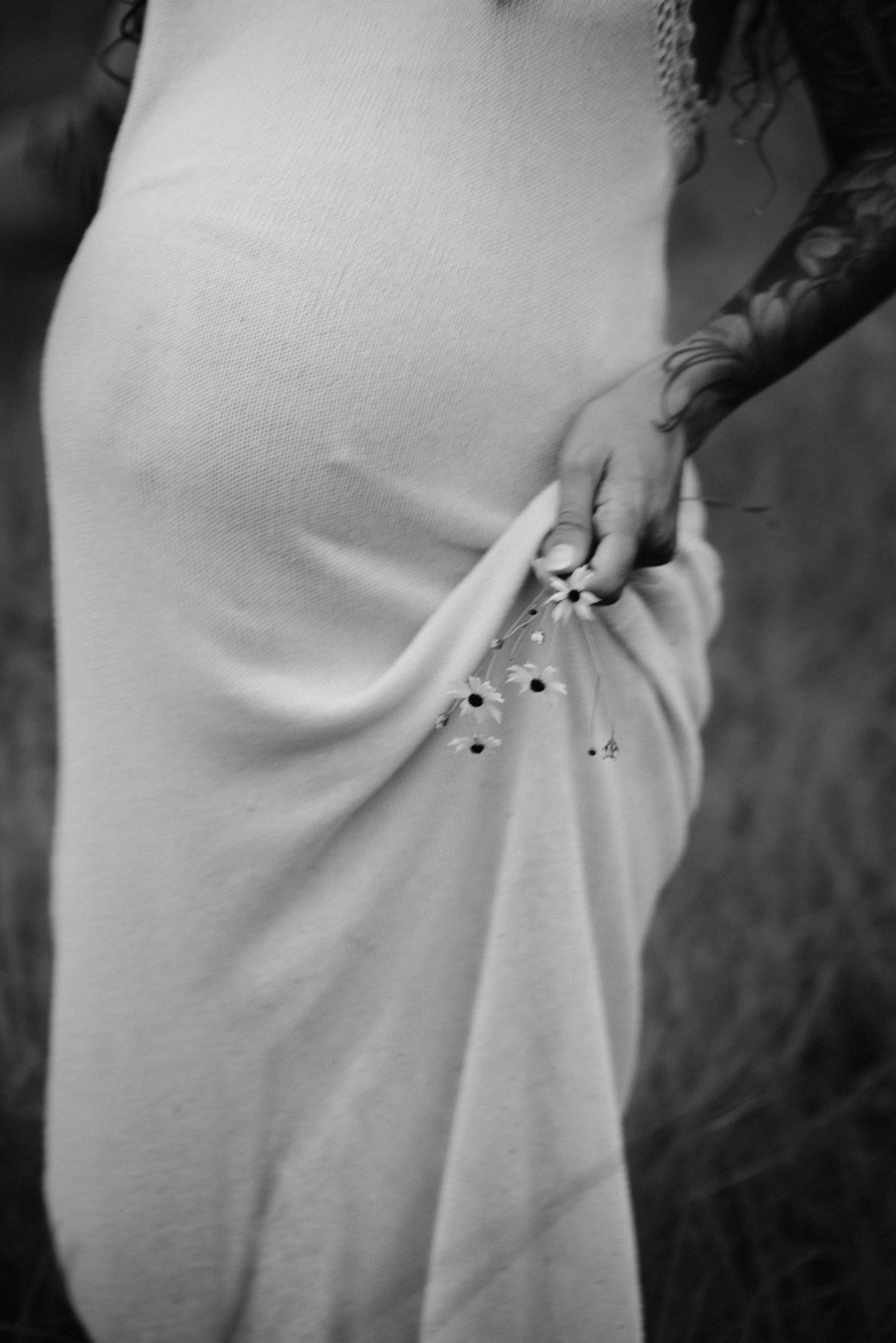 A white maternity dress with hands gently resting on the baby bump.