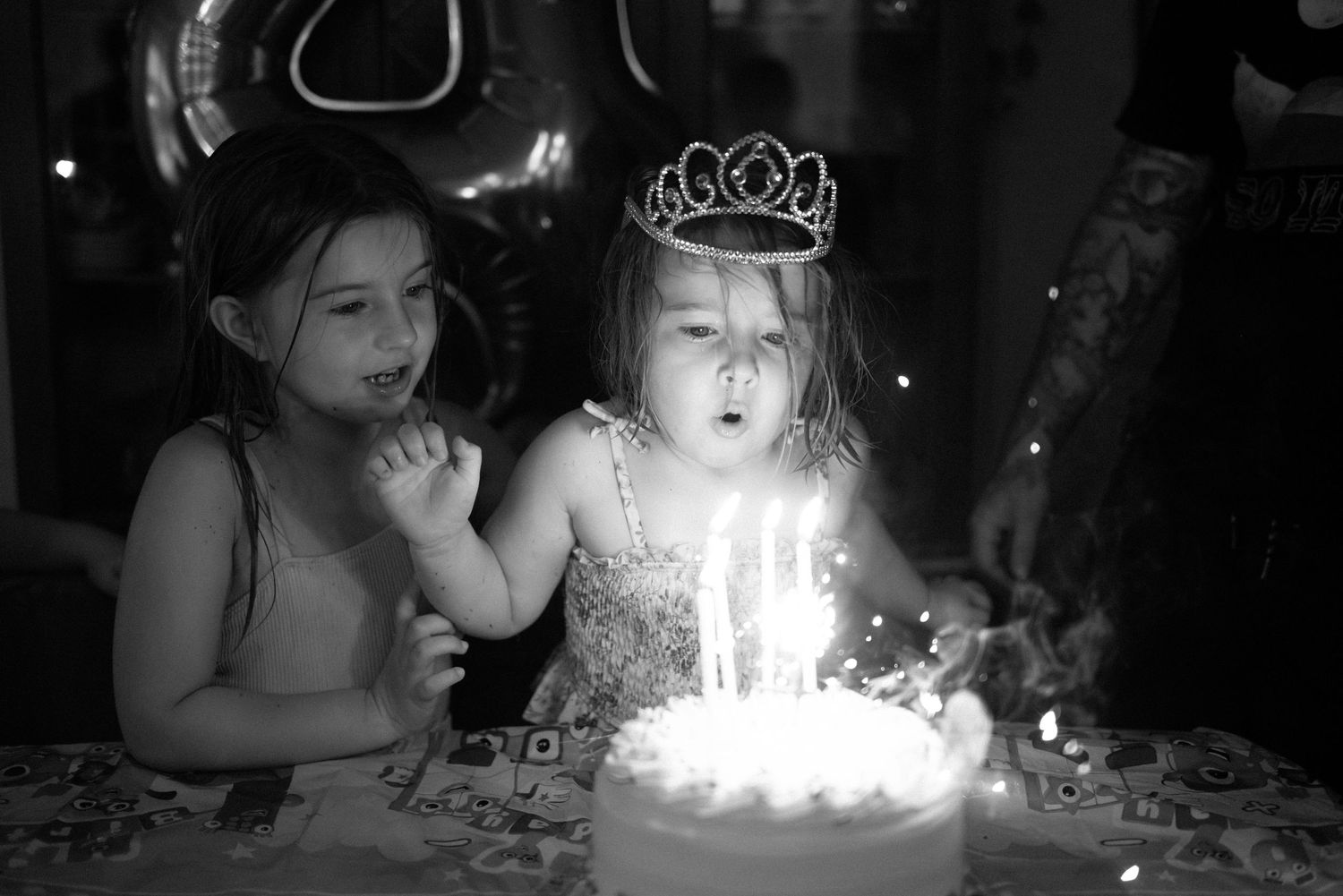 Birthday party celebration with lit candles on cake in dark room.