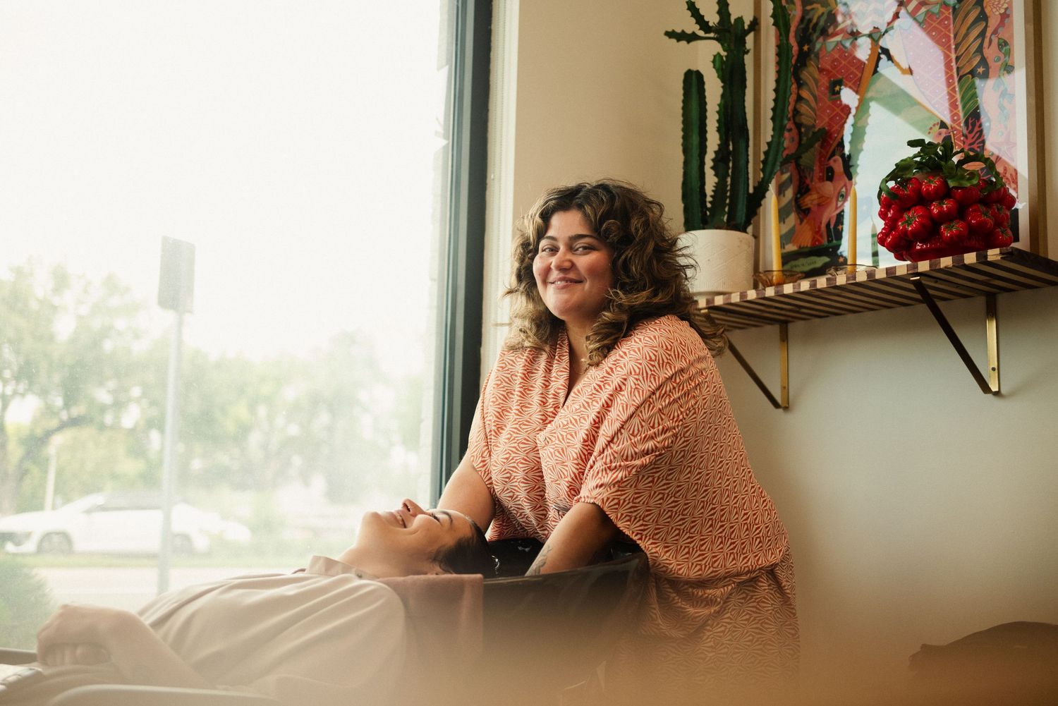 Cozy window seat with pink knit sweater and natural lighting.