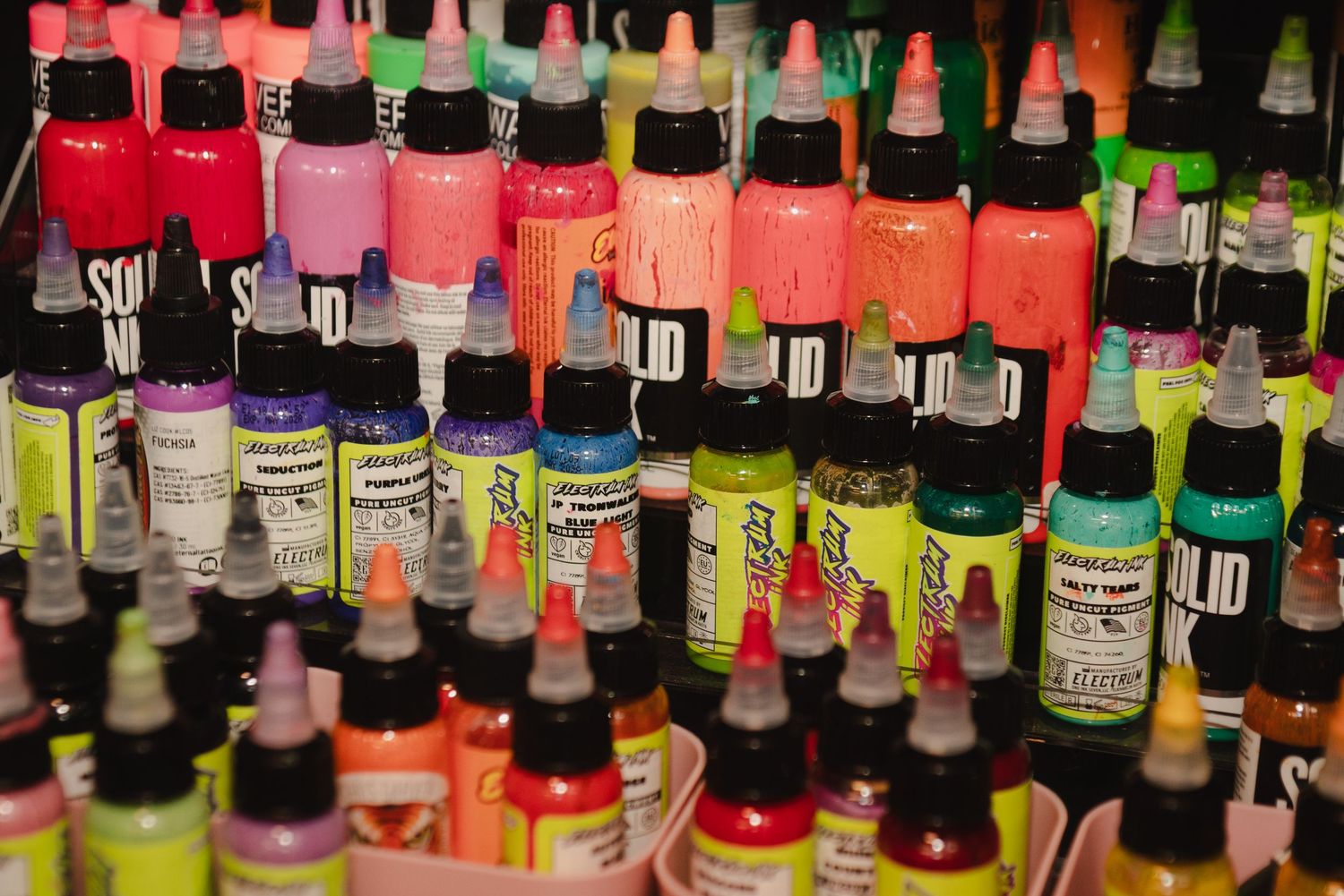 Rows of colorful ink bottles displayed on shelves with various brand labels.