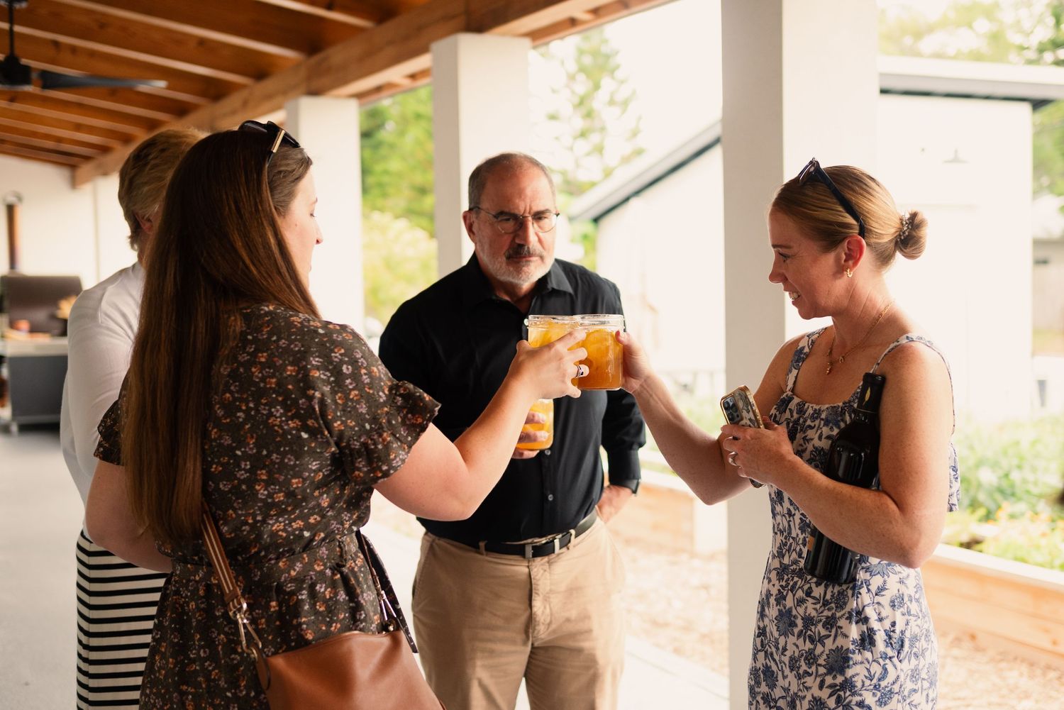 People mingling and holding drinks at an outdoor social event.