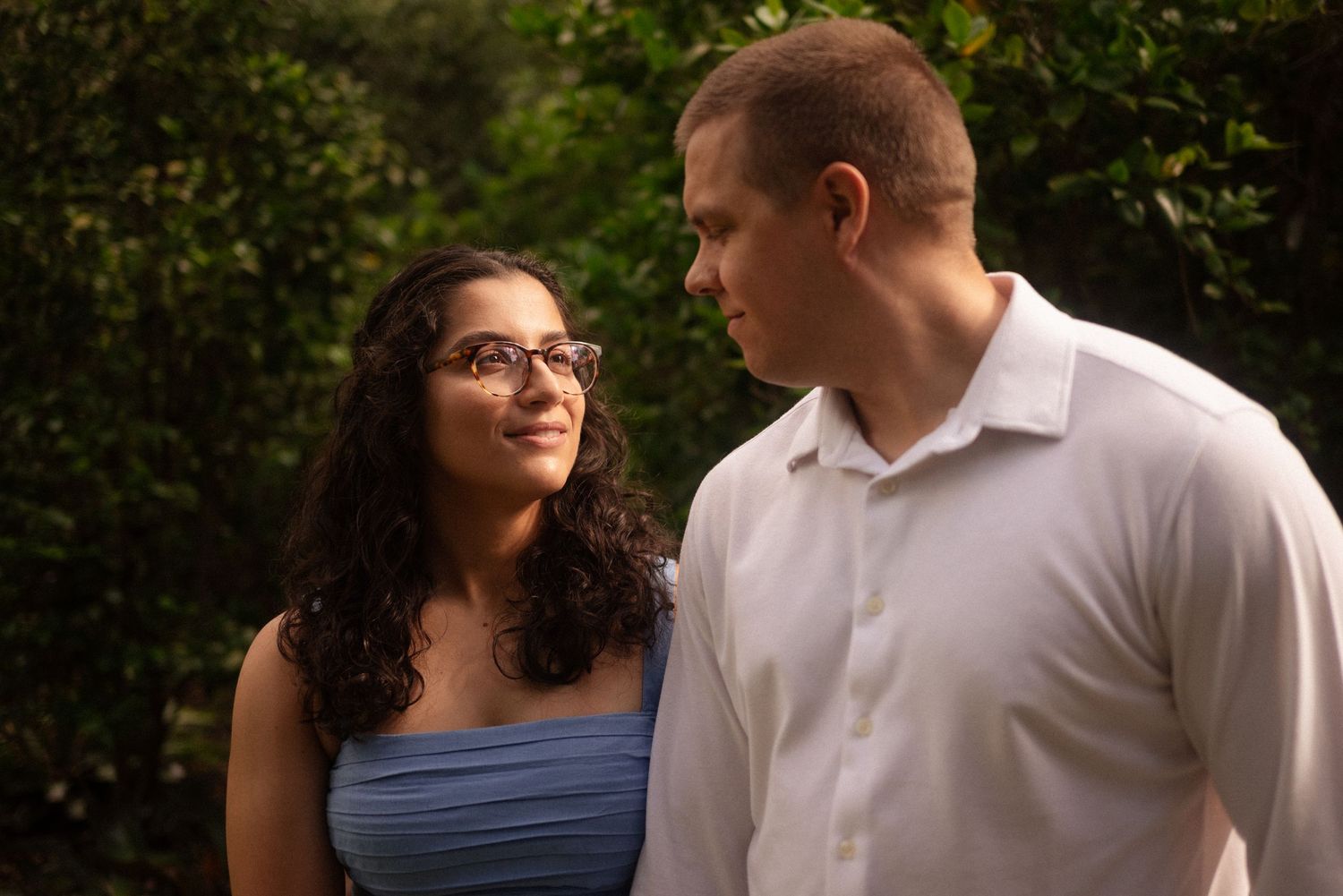 Two people sharing a tender moment while sitting outdoors in a garden setting.