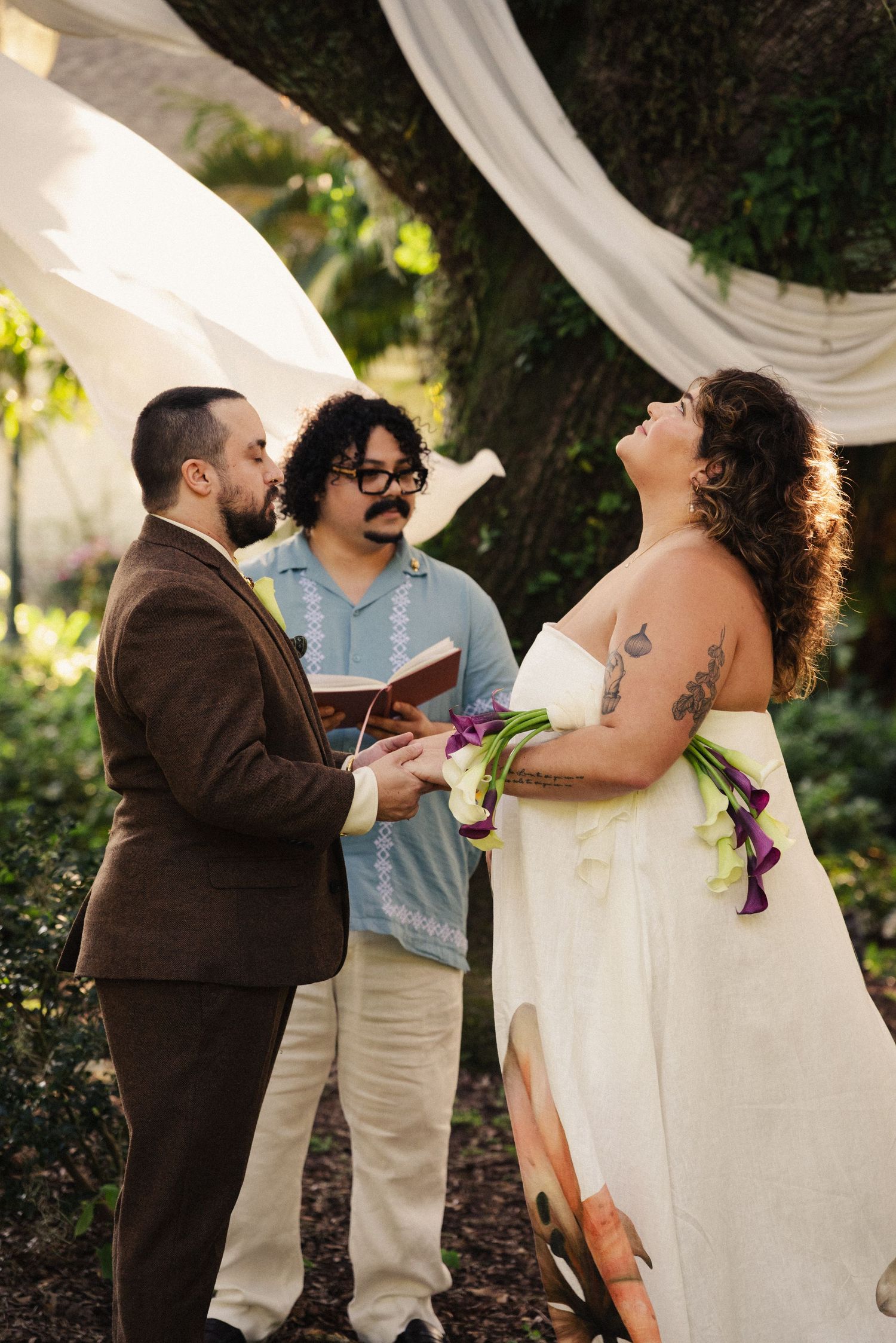 Wedding ceremony moments captured under flowing white fabric and natural greenery.