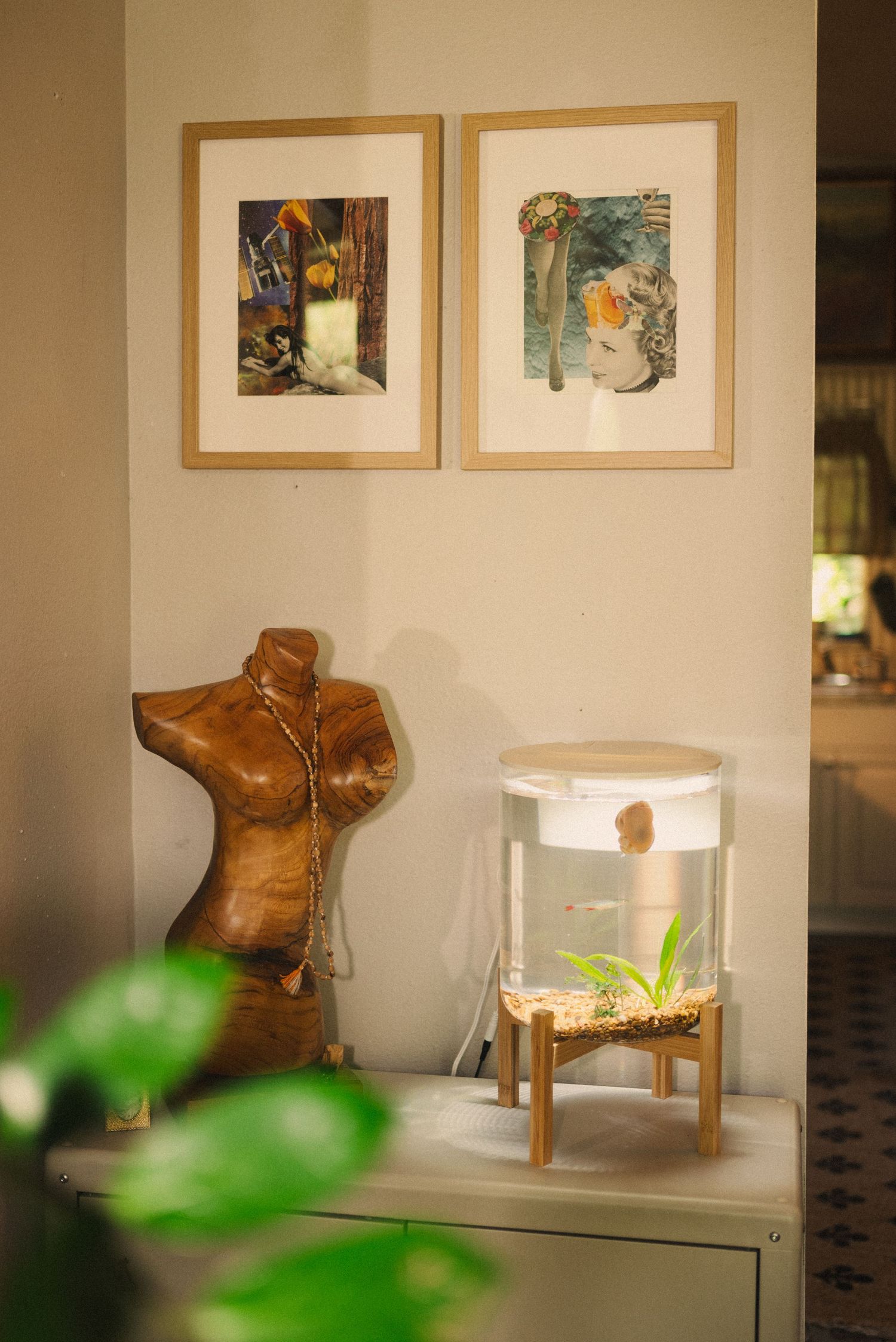 An art gallery display featuring brown leather boots and framed artwork on white walls.