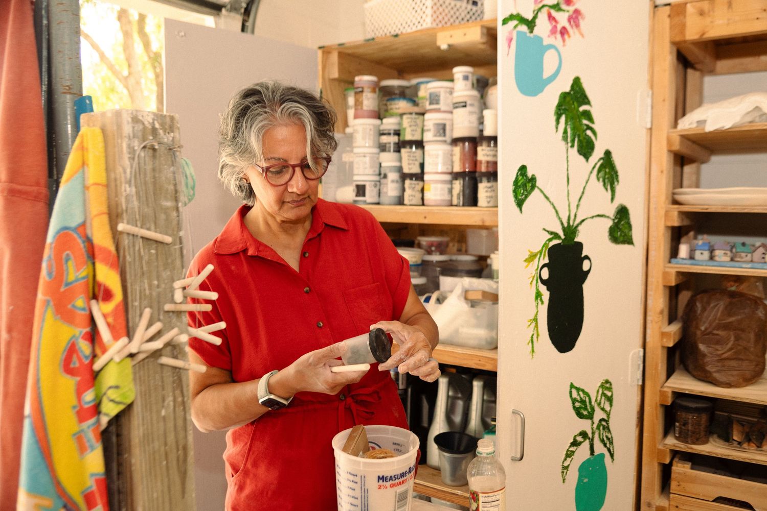 Bright pottery studio interior with wooden shelving and decorative plant elements.