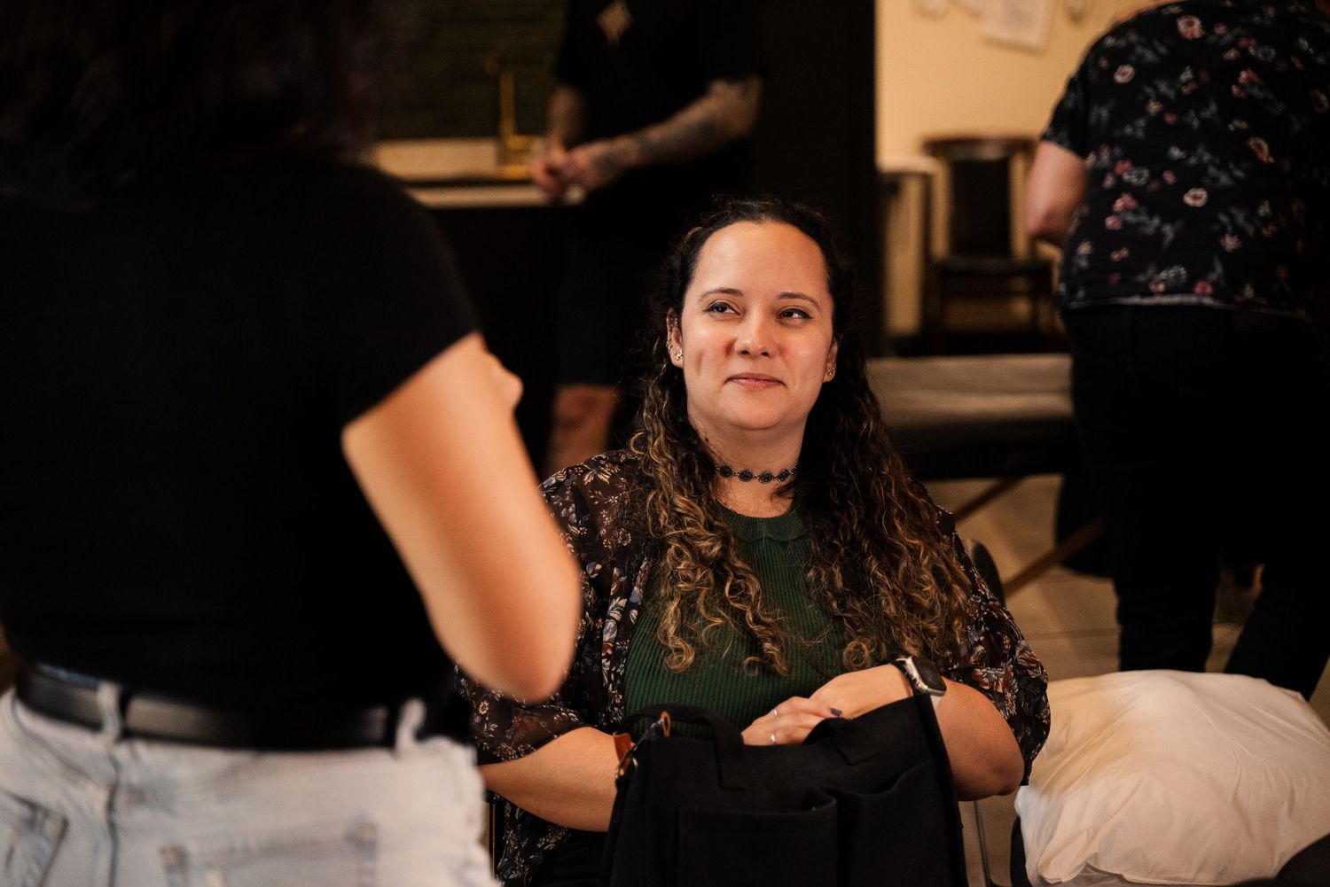 Tattoo artists working on clients in a professional studio setting with warm lighting.