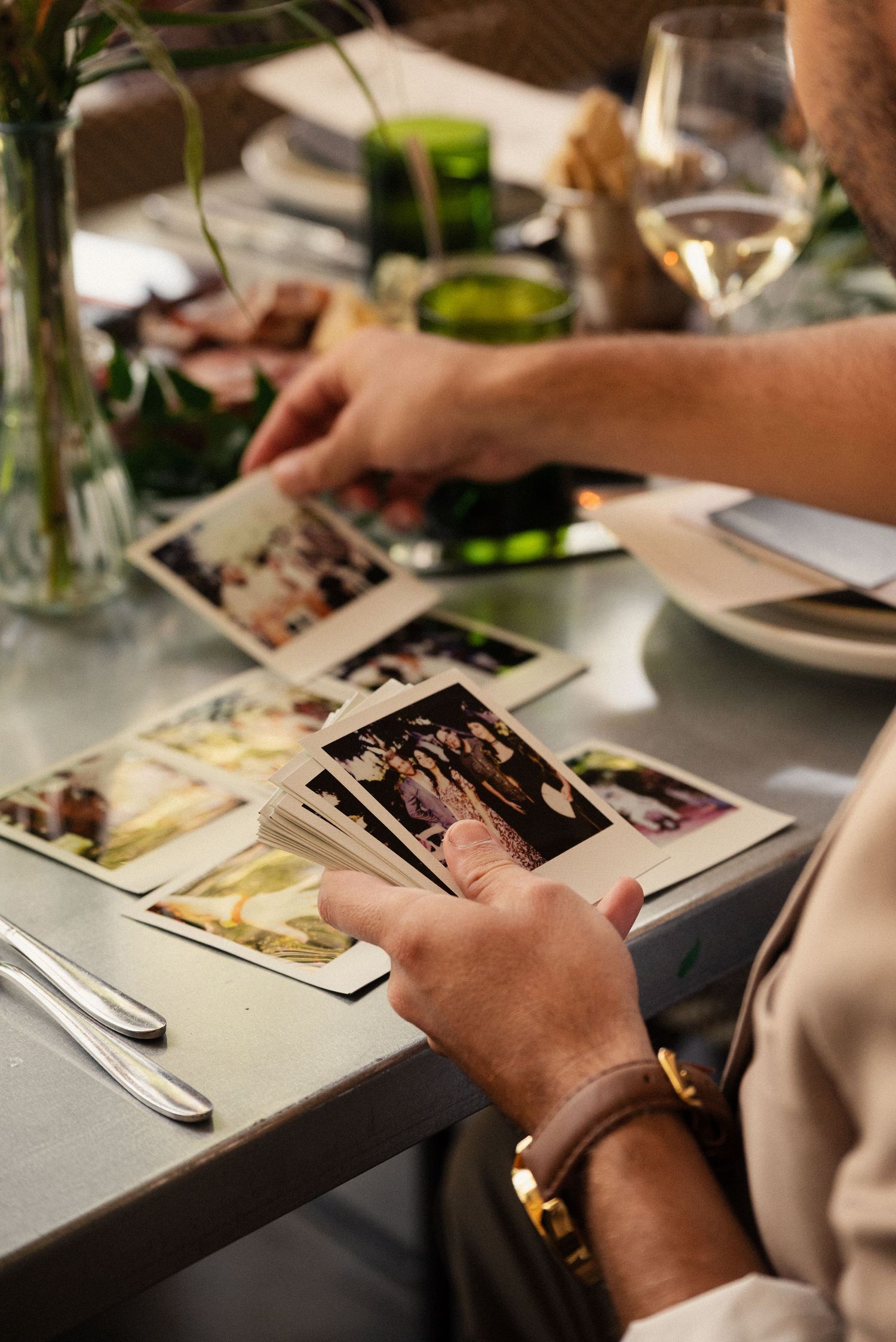 Hands browse through wedding photographs at a reception table setting.