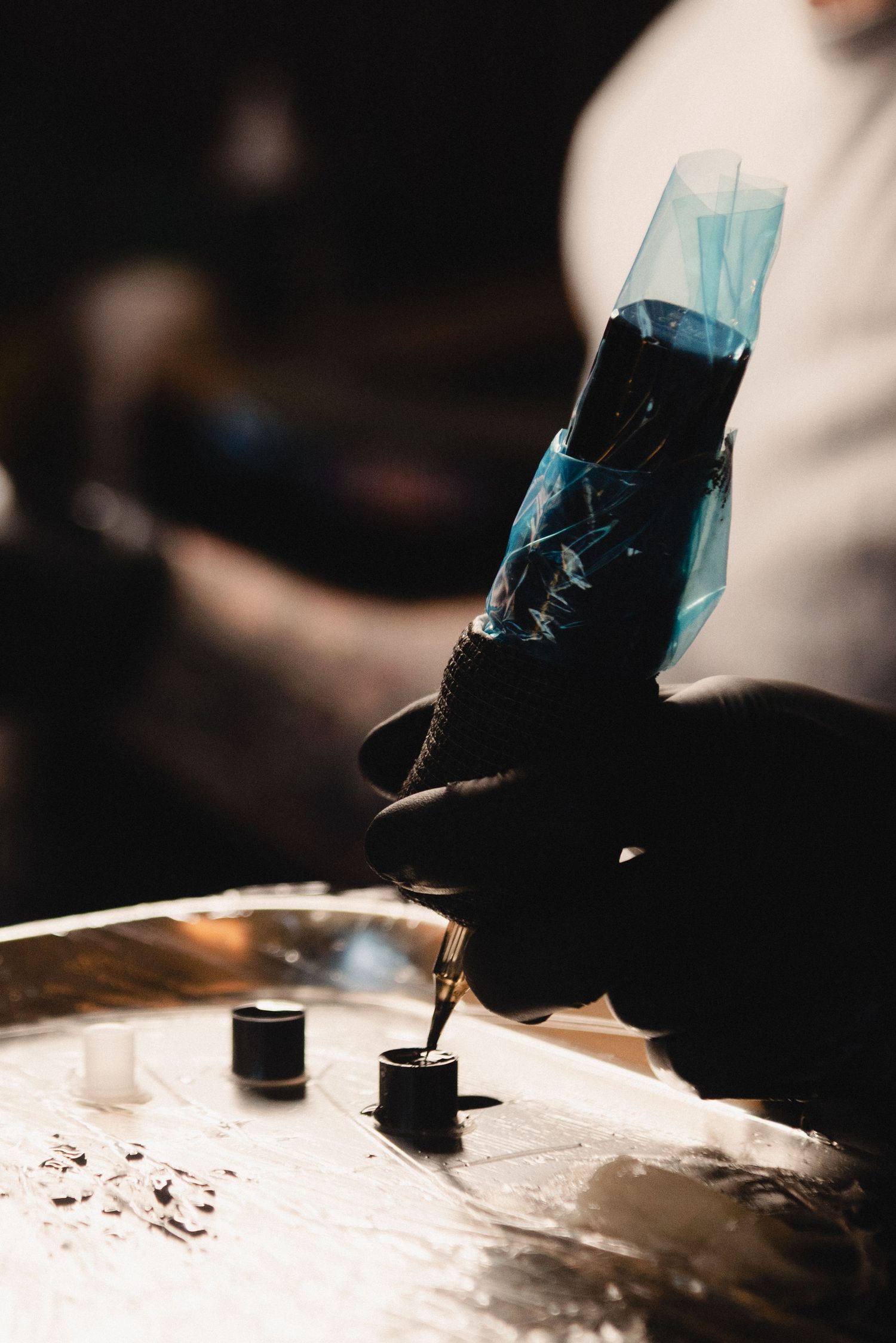 Close-up of tattoo machine applying ink in dramatic lighting conditions.