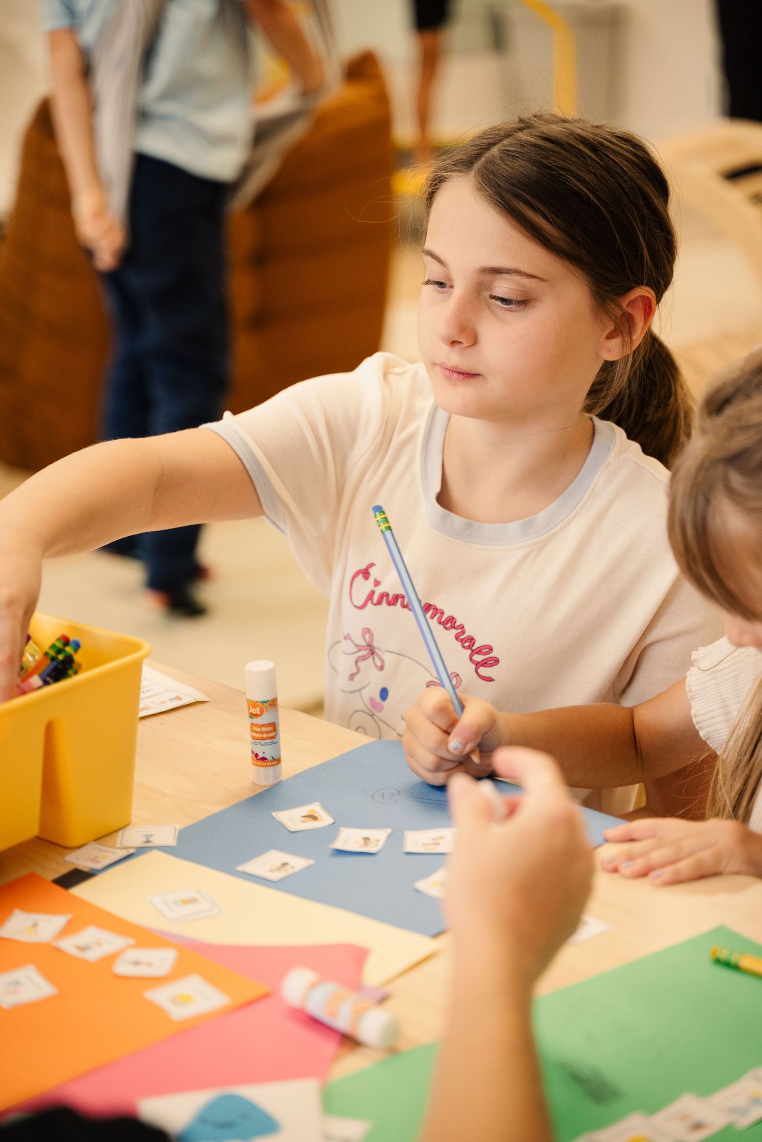 Student focused on completing a creative activity at a colorful table.