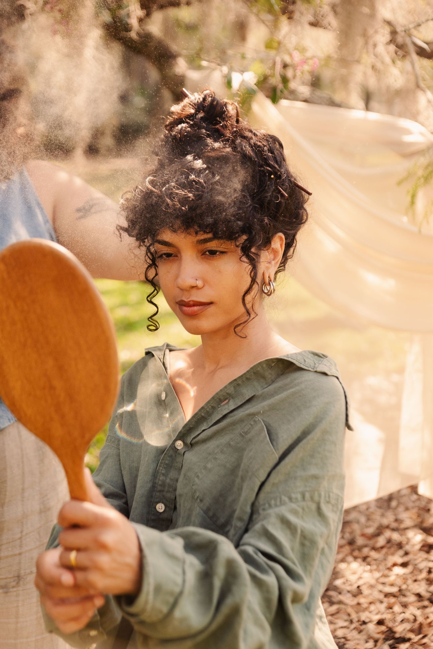 A sequence showing someone with curly hair examining a wooden spoon while sitting outdoors.