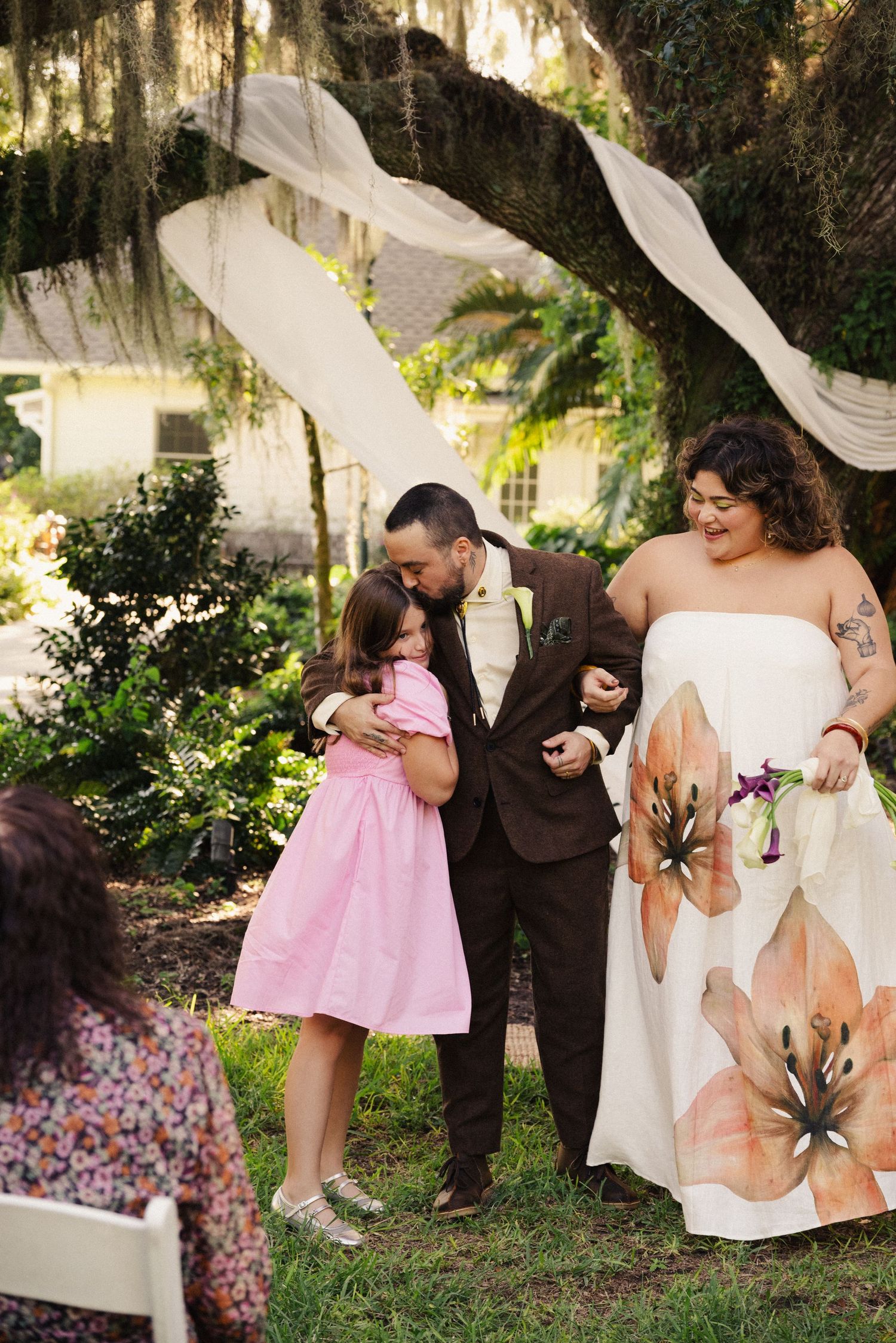 Wedding party members pose for photos in garden setting with Spanish moss.