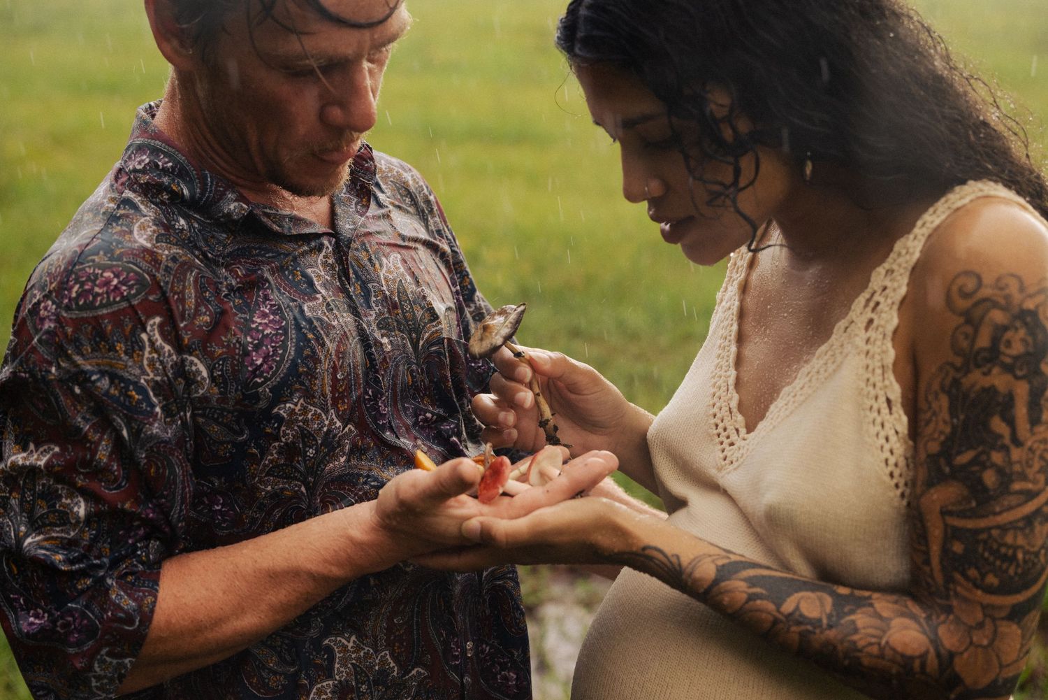 Two people sharing an intimate moment in a grassy field.