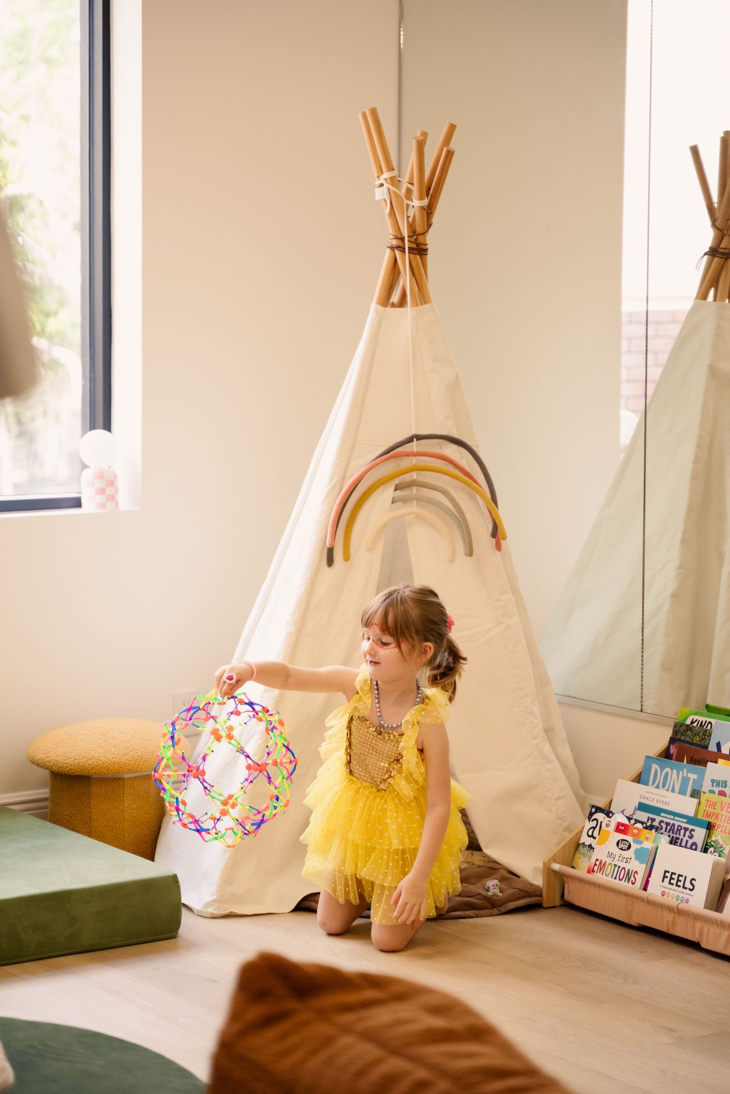 Cozy play area with teepee tents and cushions in natural sunlit room.