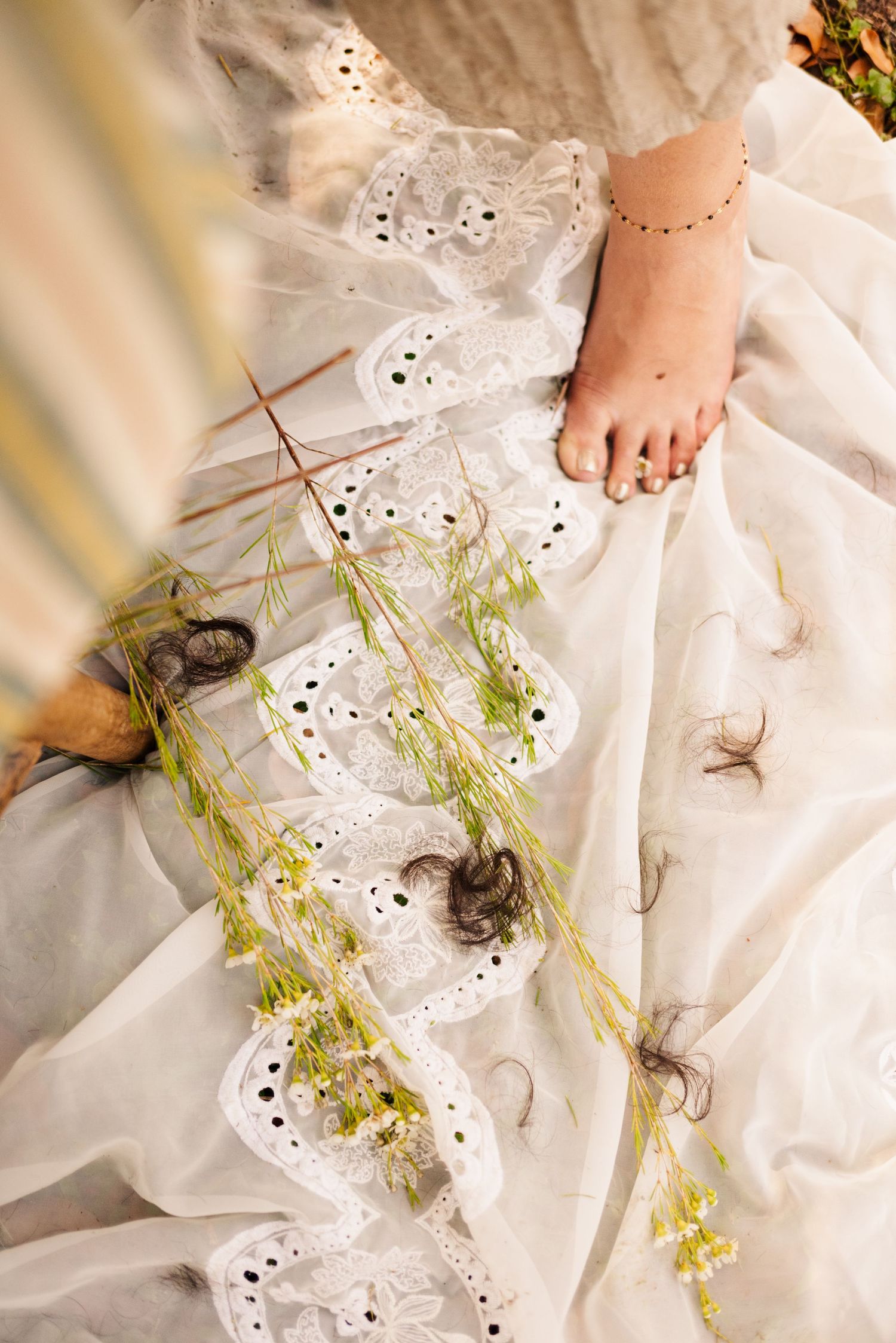 White eyelet fabric with scattered greenery and natural elements creating a delicate composition.
