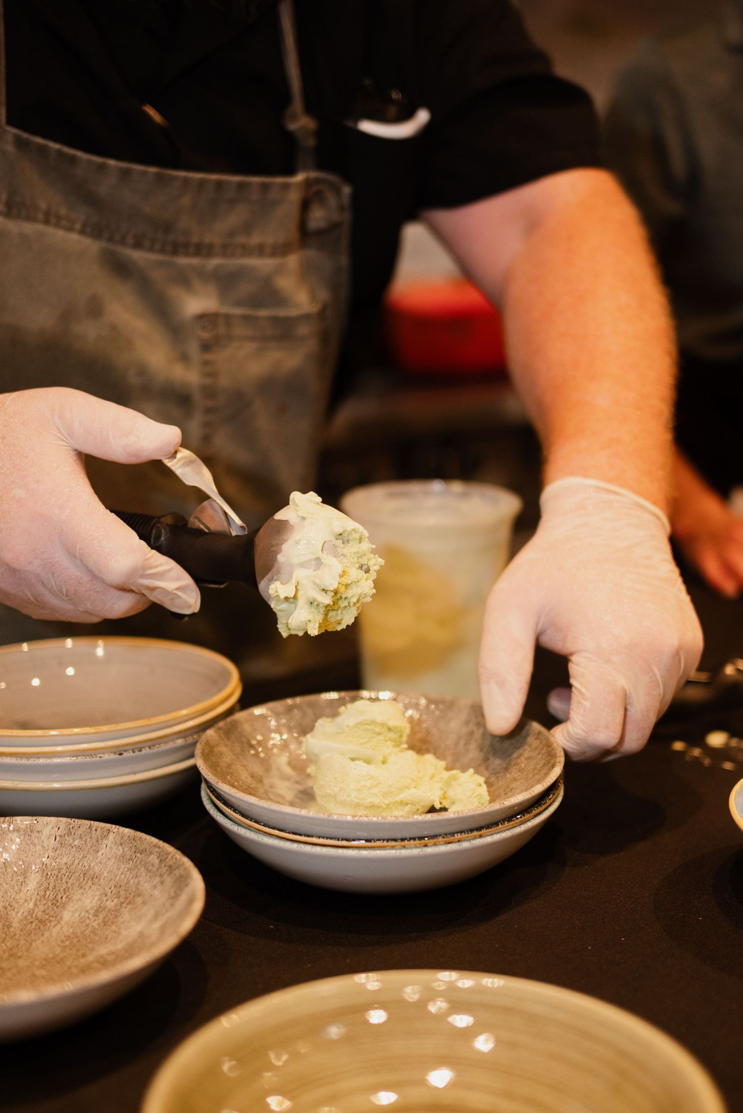 Close-up of hands plating food on gray dishes in a restaurant kitchen.
