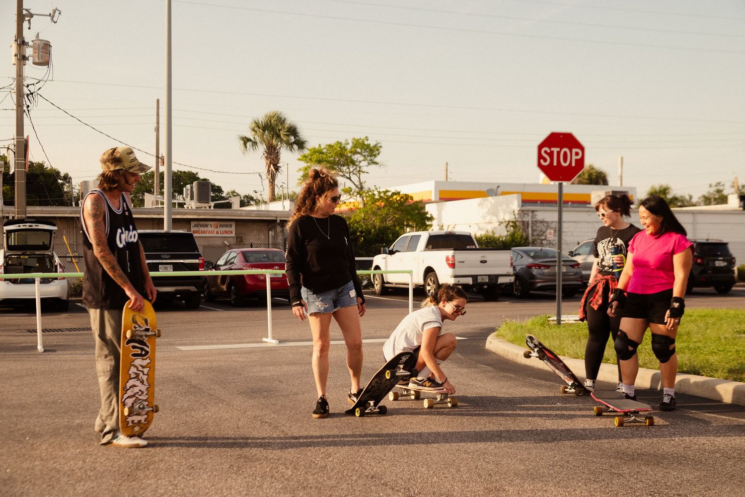 Multiple frames of skateboarders practicing tricks in a parking lot with a stop sign in the background.