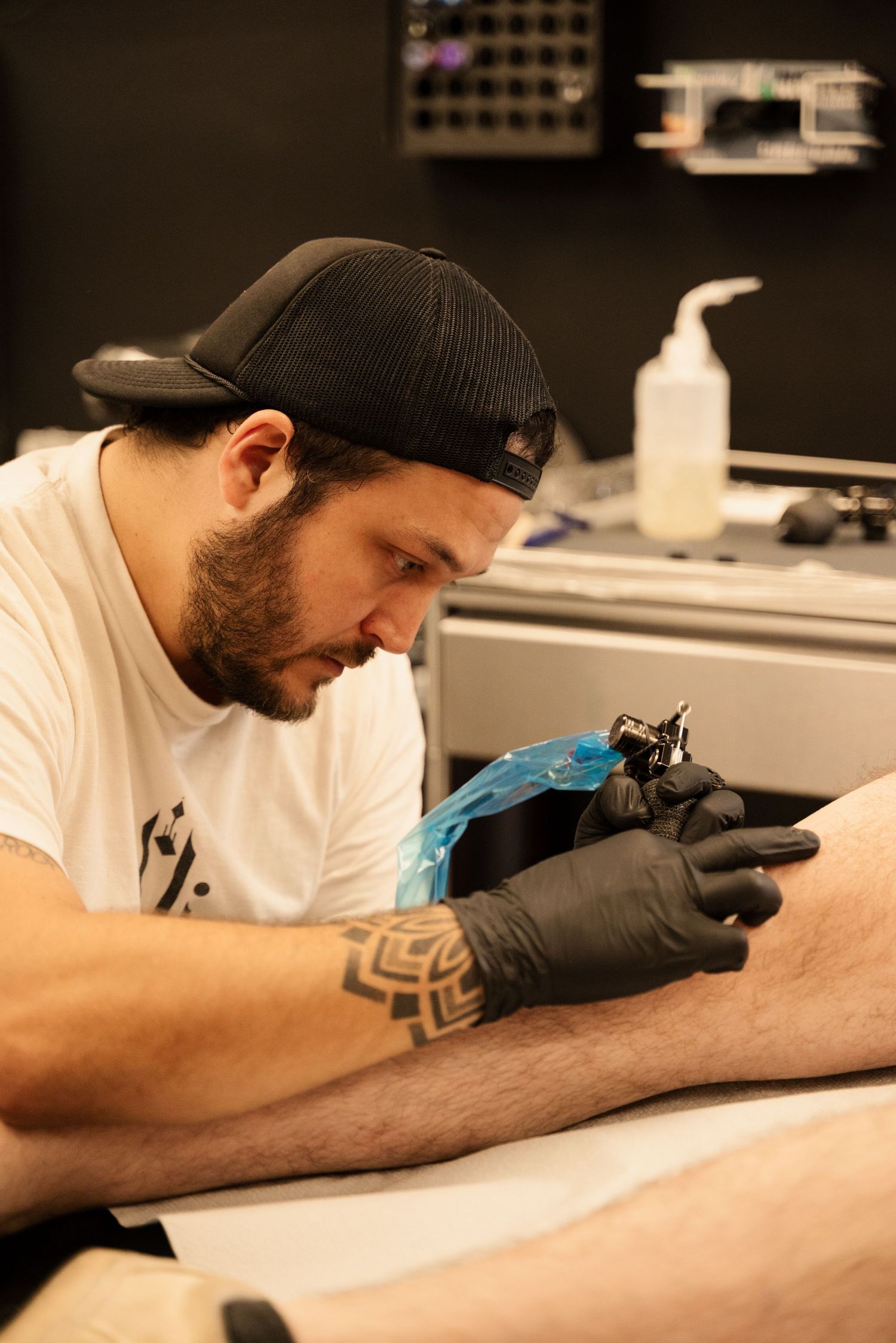 Tattoo artist wearing gloves works on creating a detailed design.
