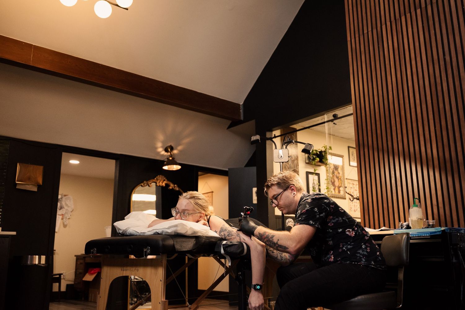 Interior view of a modern tattoo studio with pendant lighting and wood paneled walls.