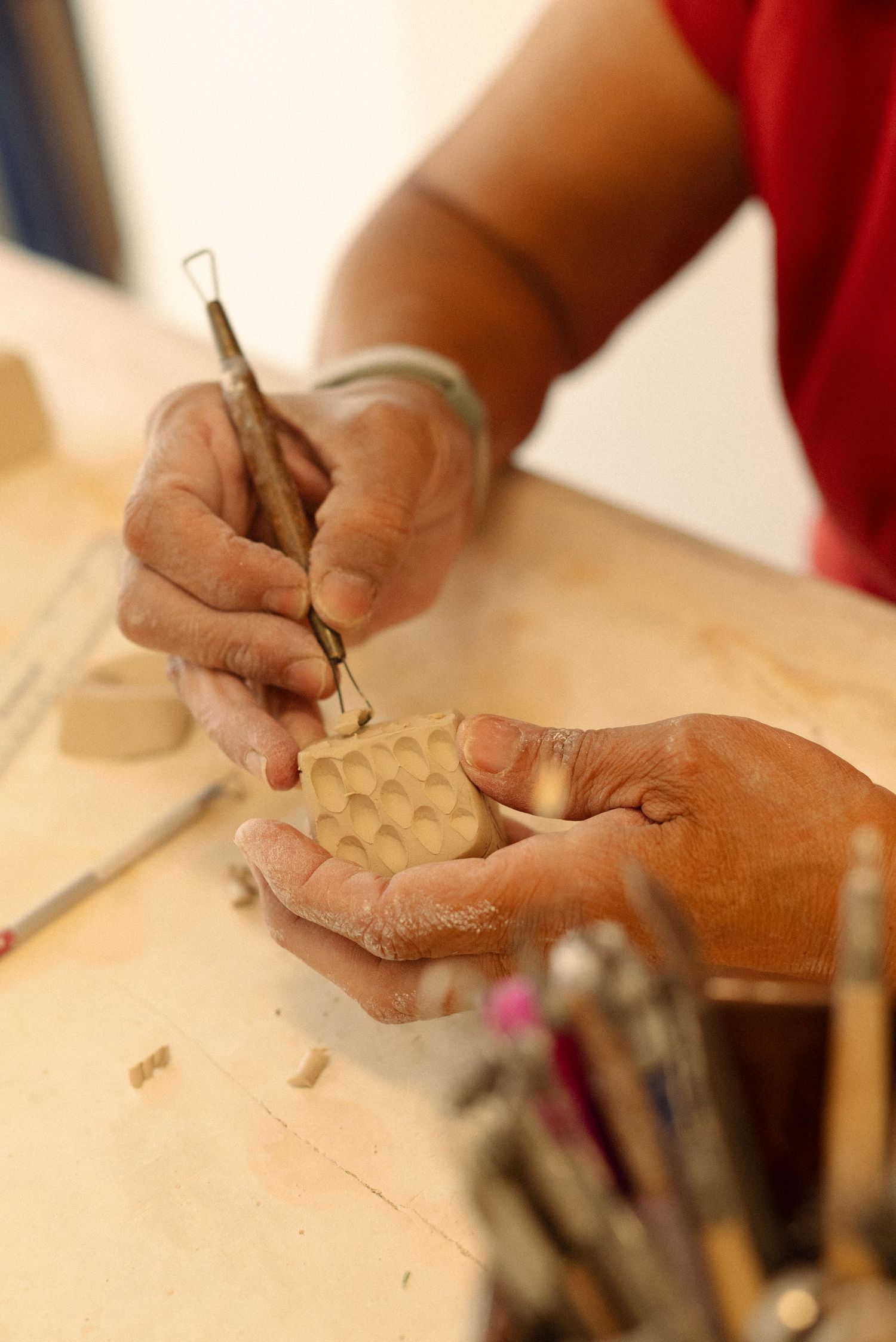Close-up view of hands working with clay on a pottery table.