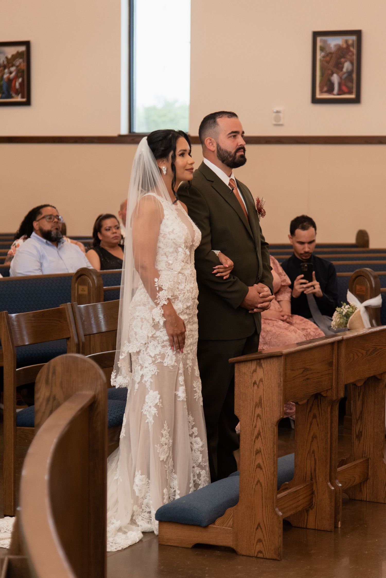 A wedding ceremony in a church with the couple standing at the altar in front of wooden pews.