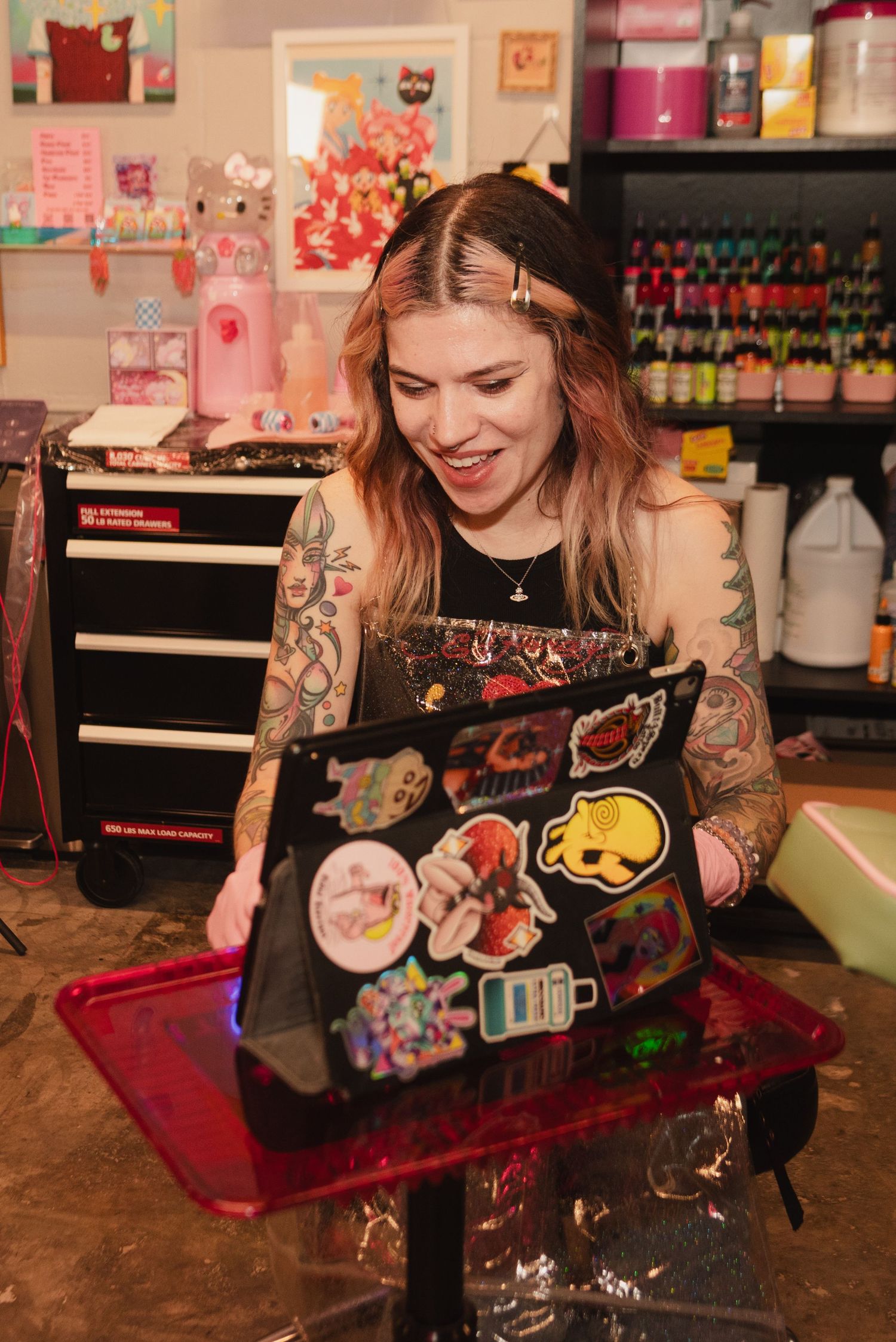 Tattoo artist working at a station with colorful supplies and equipment.