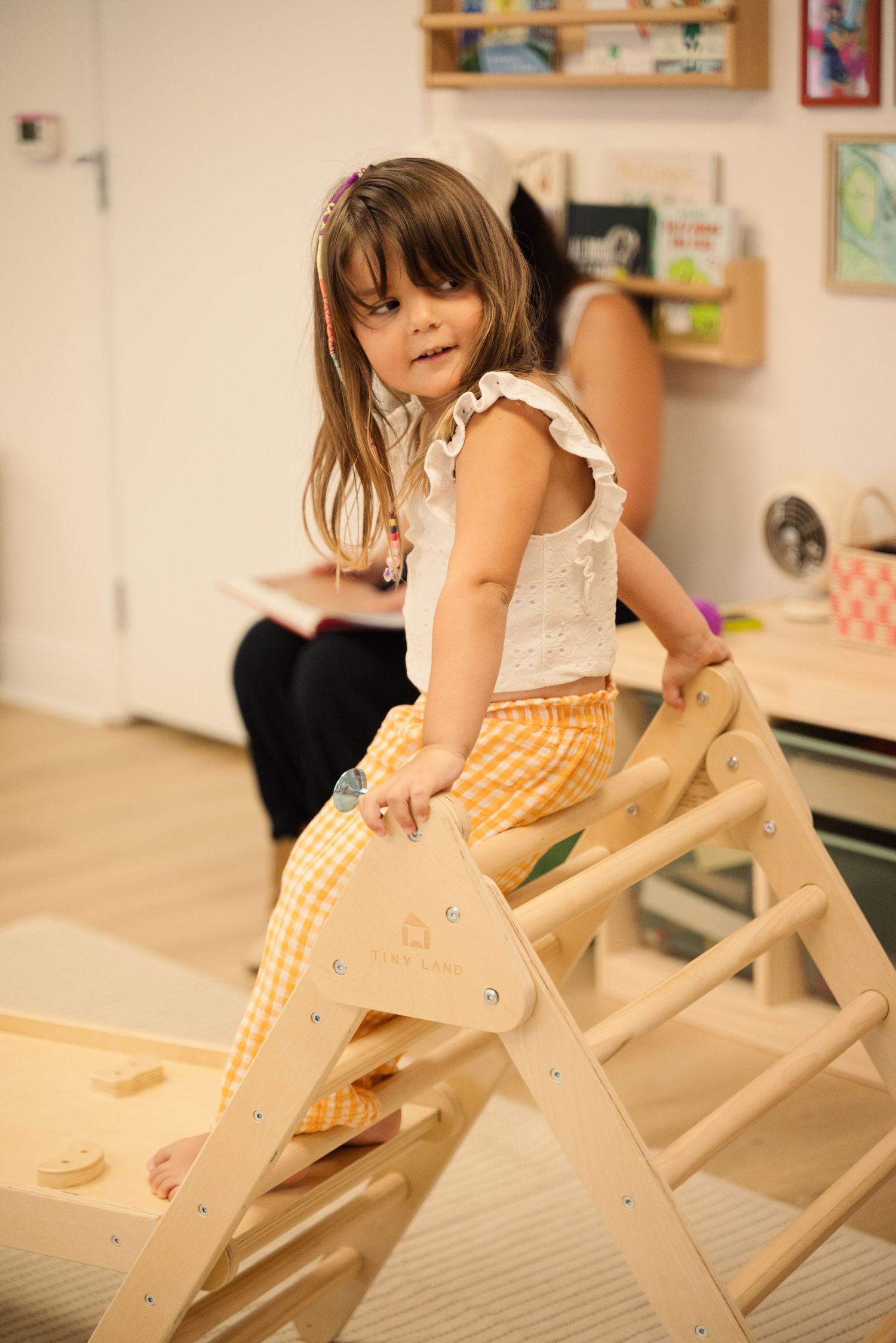 Child climbing on wooden play structure during indoor activity time.