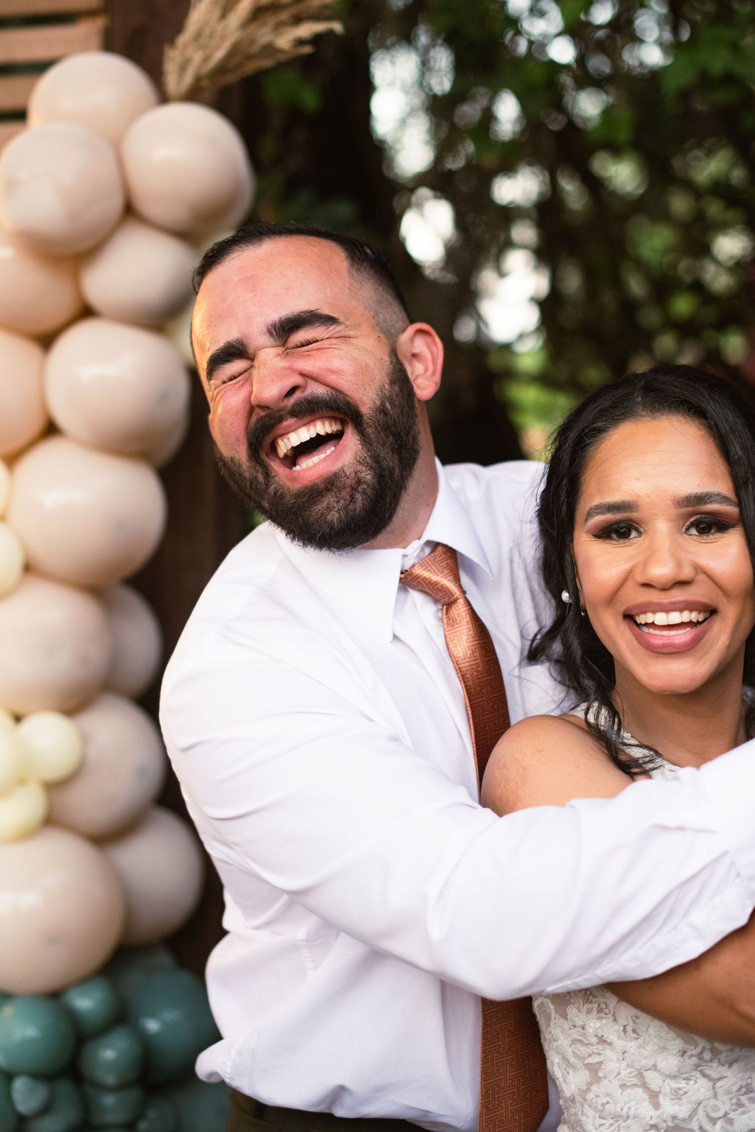 Joyful wedding couple embraces and laughs together during their celebration.