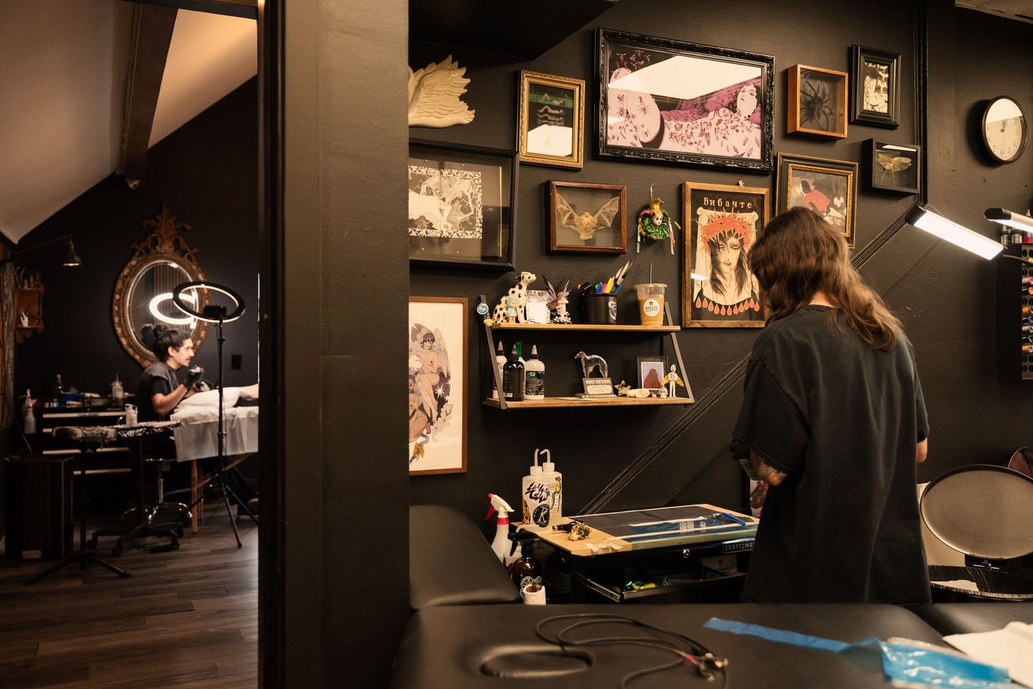 Dark interior of a tattoo studio with framed artwork and display cases along the walls.