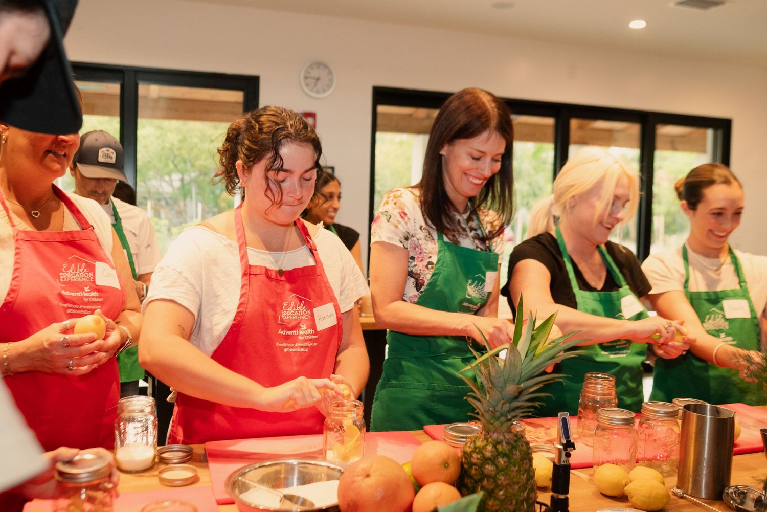 Students in red and green aprons participating in a hands-on cooking class.