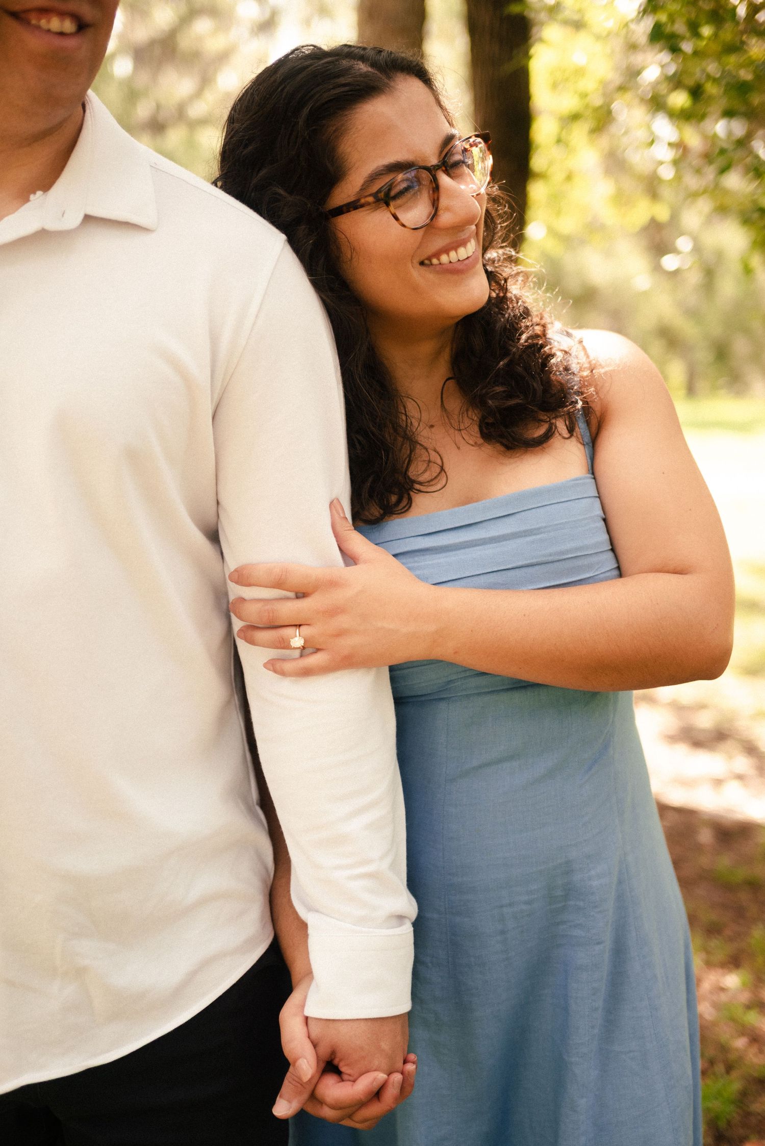 Couple in white and blue outfits sharing tender moments in a sunlit outdoor setting.