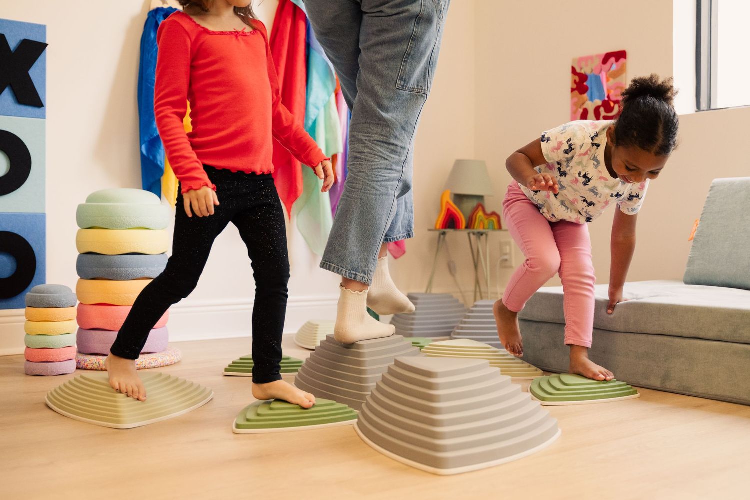 Children climbing and playing on wooden indoor playground equipment with green mats.