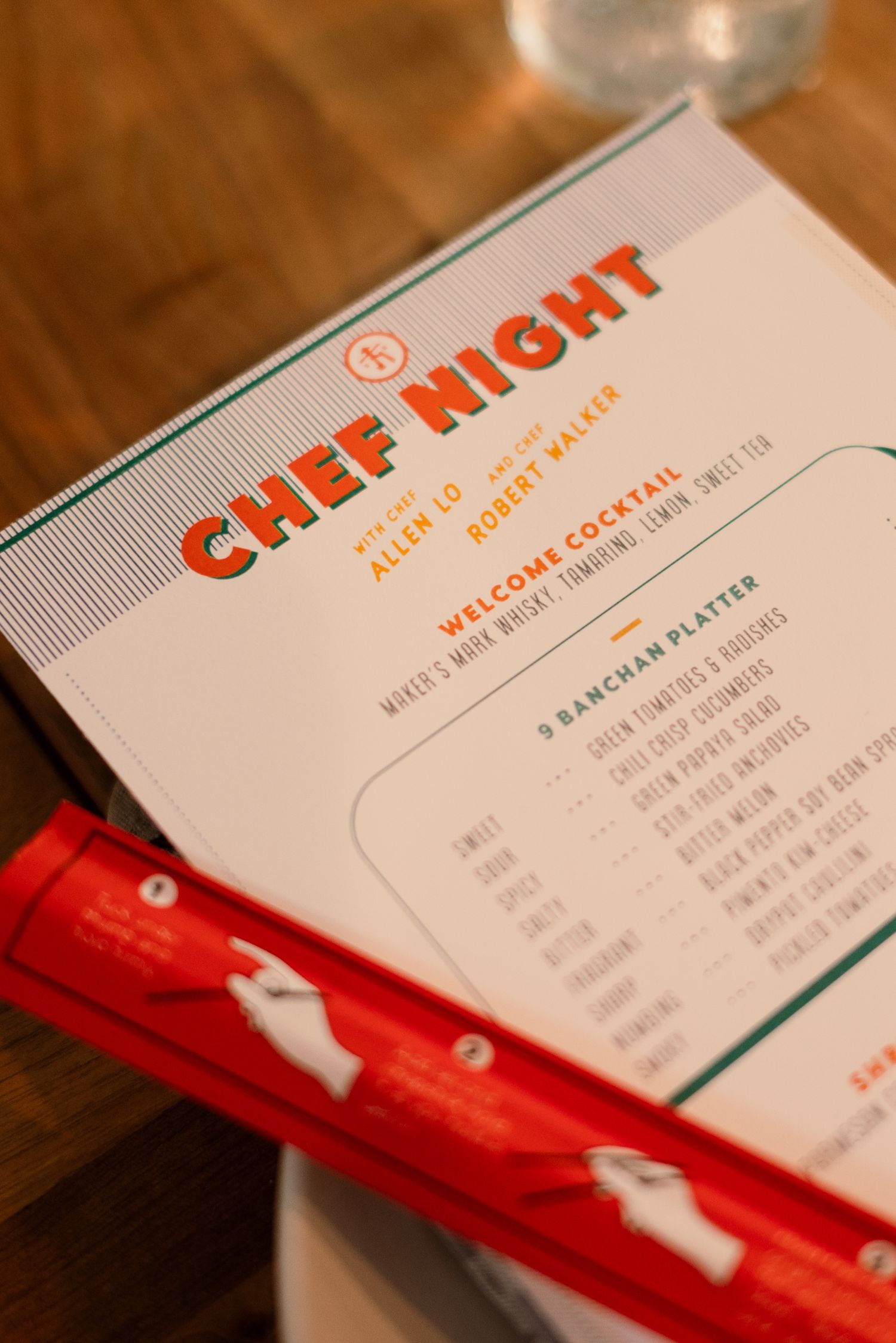 Restaurant menus with red and teal design elements displayed on wooden surface.